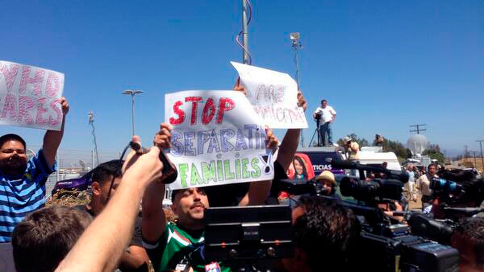 Counter-protestors hold pro-immigrant banners as protestors stand in the road blocking a bus carrying 140 immigrants on the way to be processed at the Murrieta border patrol station on Tuesday, July 1, 2014. The migrants are bused to a border patrol facility in Murrieta, about an hour north of San Diego, for processing. Federal immigration authorities there will determine whether they will be held or released pending deportation proceedings.(AP Photo/The Press-Enterprise, Sarah Burge)