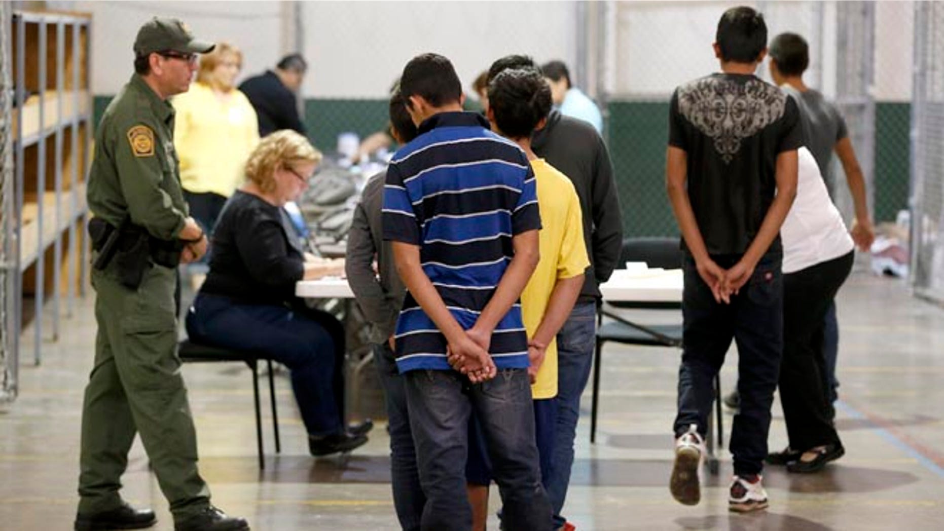 Boys wait in line to make a phone call as they are joined by hundreds of mostly Central American immigrant children that are being processed and held at the U.S. Customs and Border Protection Nogales Placement Center on Wednesday, June 18, 2014, in Nogales, Ariz.