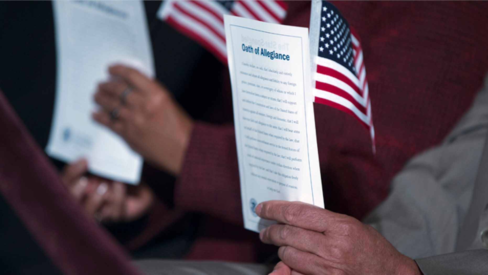 In this Dec. 15, 2015, photo, participants hold the "Oath of Allegiance" and American flags during a naturalization ceremony attended by President Barack Obama at the National Archives in Washington. More Americans favor than oppose a pathway to citizenship for immigrants who are living in the United States illegally, a new Associated Press-GfK poll shows. While most Republicans oppose such a path to citizenship, it doesn't seem to be a dealbreaker issue for them. (AP Photo/Evan Vucci)