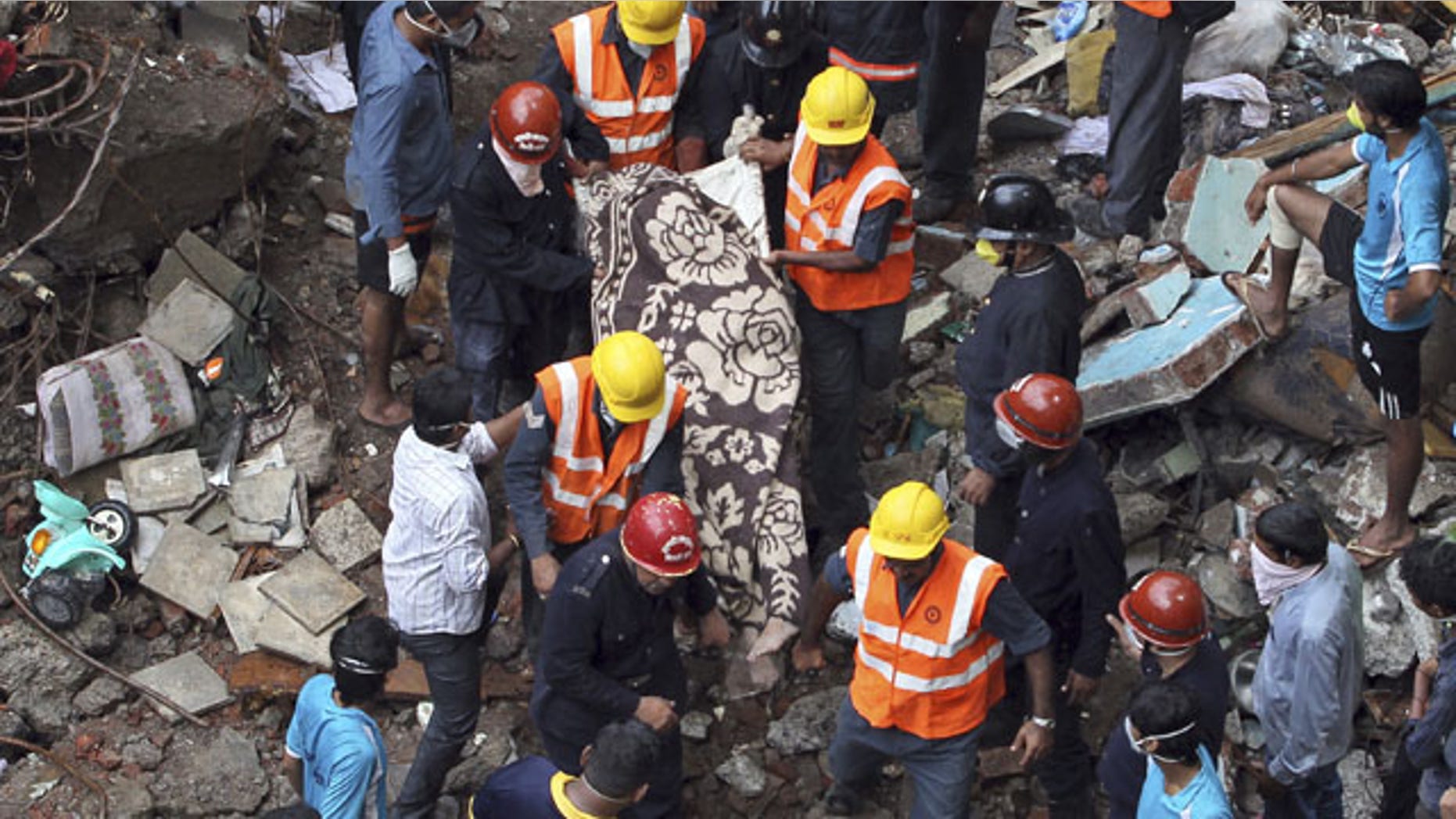 September 28, 2013: Rescue workers carry a dead body out of the debris of a building that collapsed in Mumbai, India.