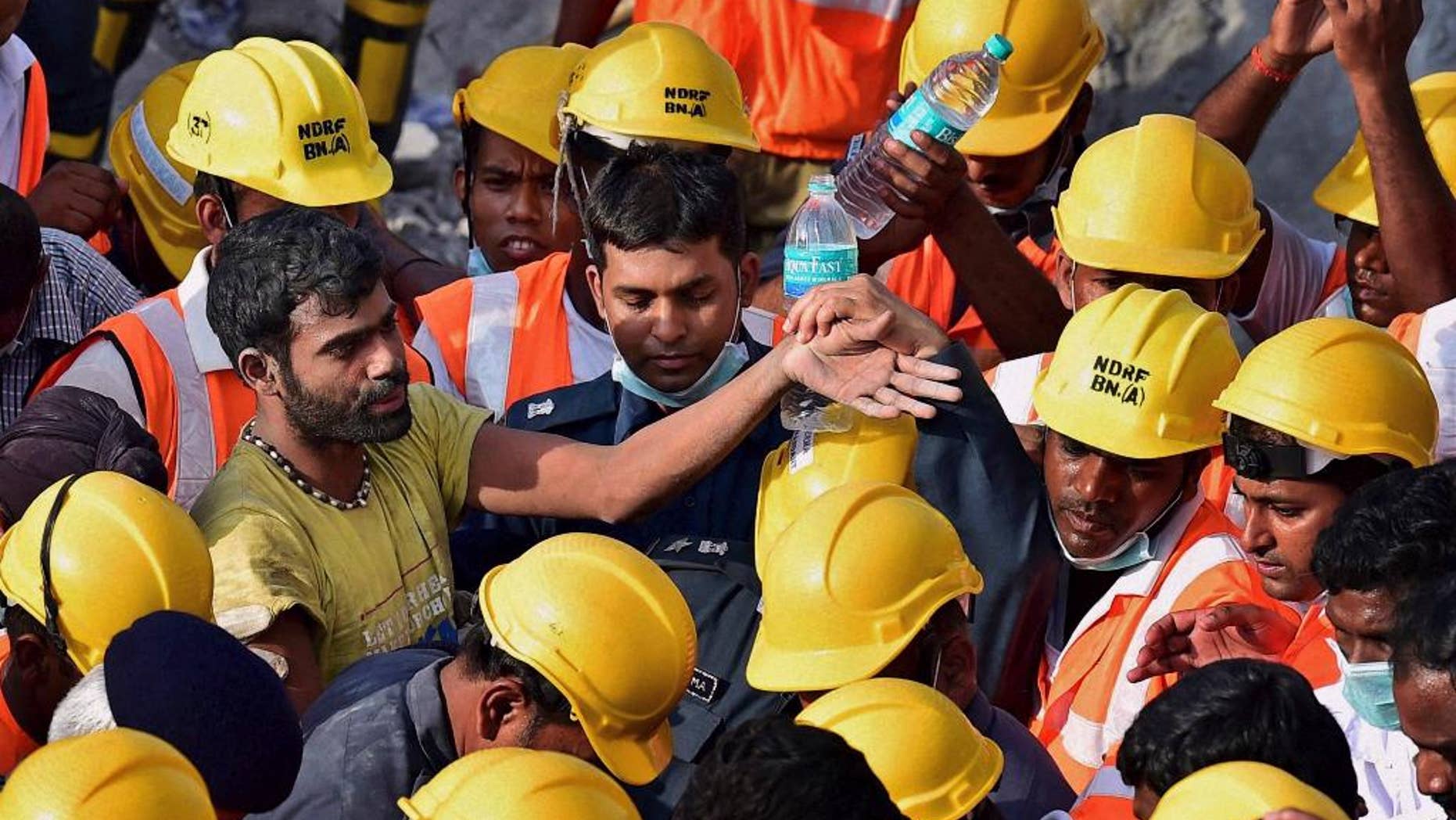 In this Tuesday, July 1, 2014 photograph, India’s National Disaster Response Force personnel stand around a man, left, they rescued from beneath the debris of a building that collapsed Saturday on the outskirts of Chennai, India. Rescuers pulled seven more survivors from under the concrete ruins of a collapsed 11-story building on Tuesday, three days after it toppled and killed dozens of people in southern India, officials said. (AP Photo)