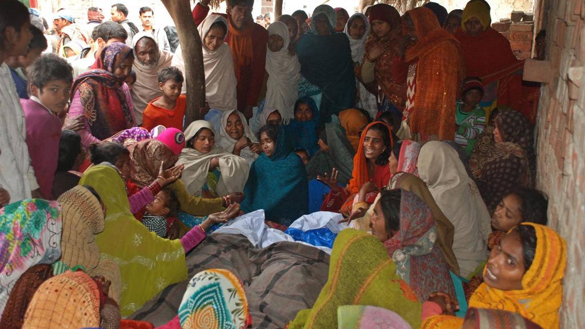 Indian women mourn around the bodies of two men, who died after consuming a bad batch of bootleg liquor in Datli village, about 30 kilometers (almost 20 miles) southwest of Lucknow, India, Tuesday, Jan. 13, 2015. More than 25 people were killed and at least 160 others hospitalized, officials said Tuesday. Many of the victims were among more than 200 people who had gathered to watch a cricket match Sunday evening in the village. (AP Photo/Sanjay Sonkar)