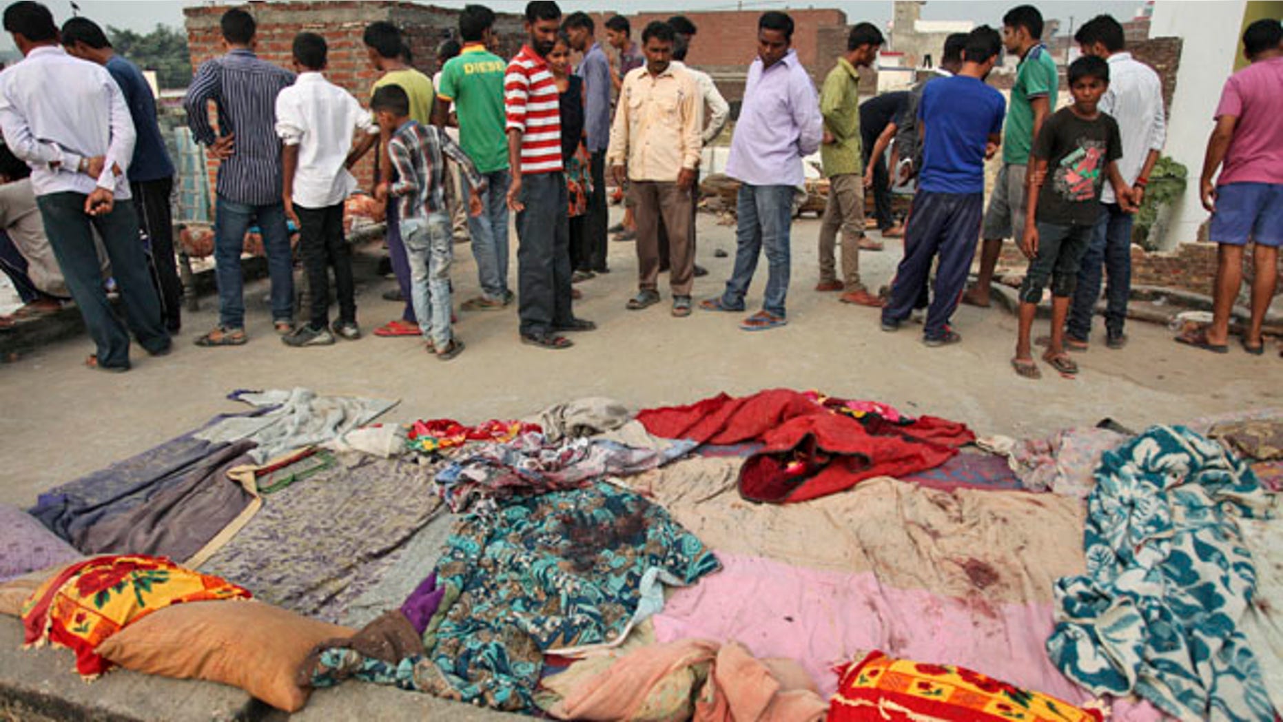October 6, 2014: Indian villagers gather near bed sheets stained with blood in alleged firing from the Pakistans side while the residents were asleep on roof of their house, at Masha da kothe village, in Arnia Sector near the India-Pakistan international border, about 30 miles from Jammu. (AP Photo/Channi Anand)