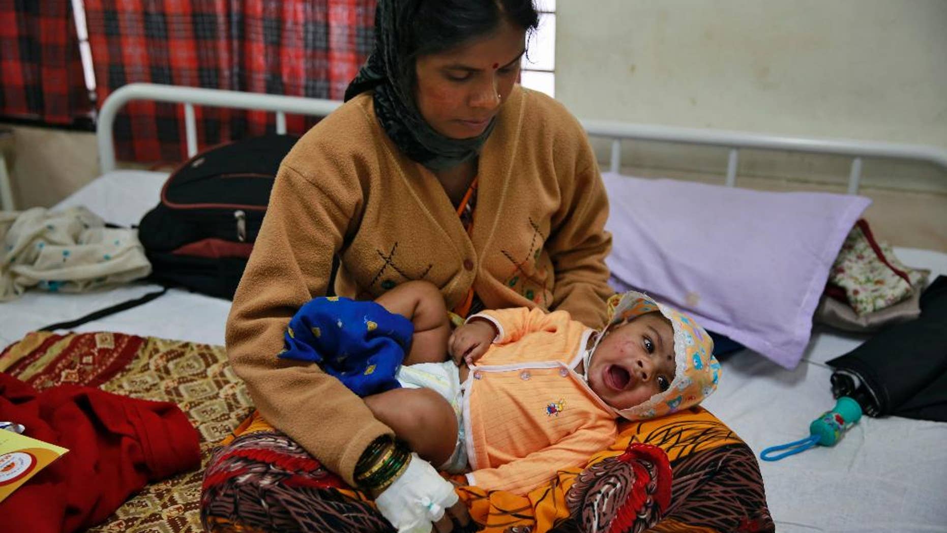 Landslide survivor Pramila Lende holds her son Rudra who was injured in the same landslide, at a hospital in Manchar, in the western Indian state of Maharashtra, India, Friday, Aug. 1, 2014. One of the few people pulled alive from the rubble in the hours after the landslide were Lende and her 3-month-old son. Lende said she was feeding her son when she heard the roar of earth and mud ripping down the hillside. Rescuers searching for dozens of people still missing after the landslide. Chances of finding anyone alive were increasingly slim. (AP Photo/Rafiq Maqbool)