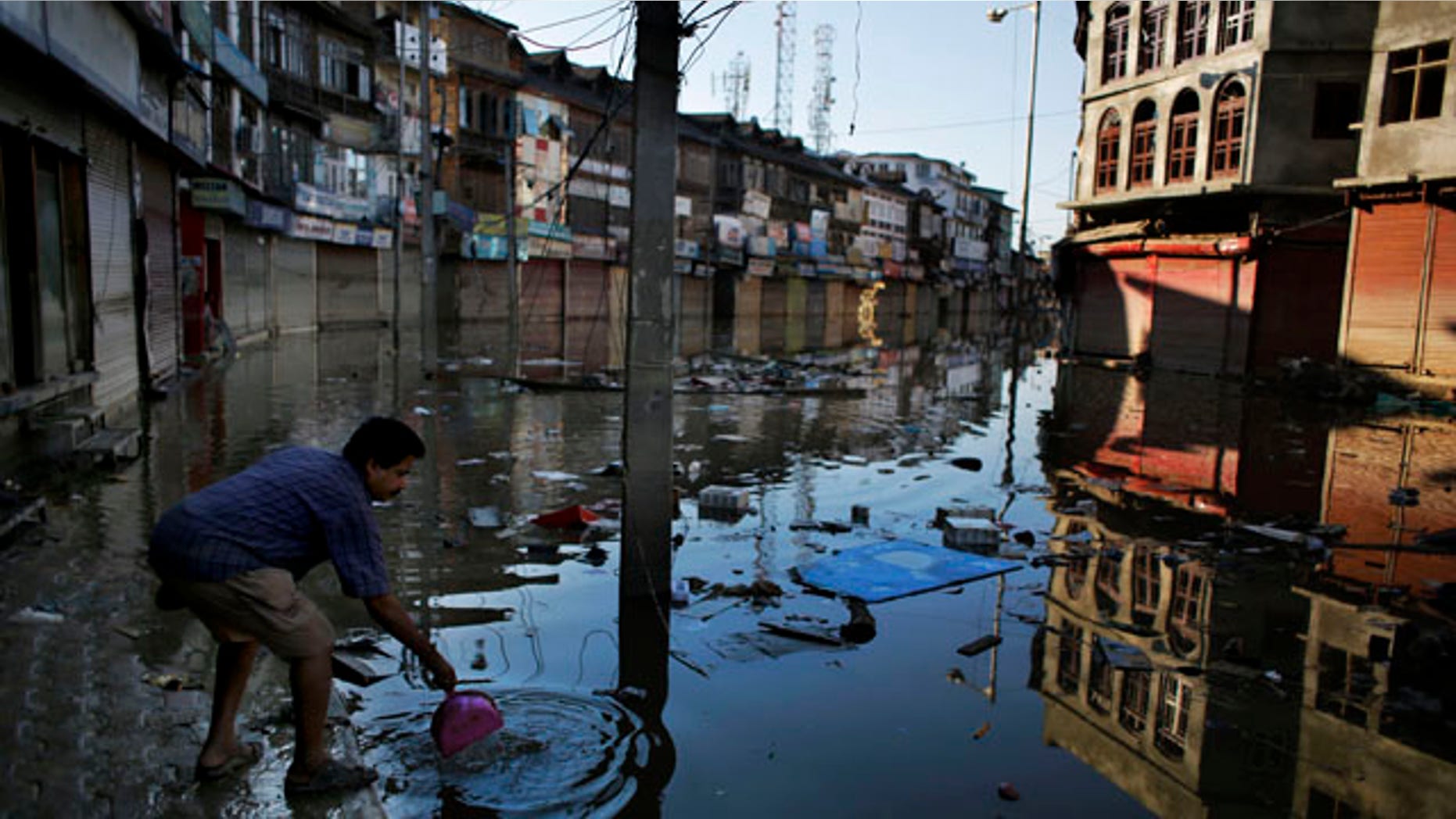 September 16, 2014: A shopkeeper throws the silt he removed from his shop into the receding flood waters in Srinagar, Indian-controlled Kashmir. (AP Photo/Altaf Qadri)