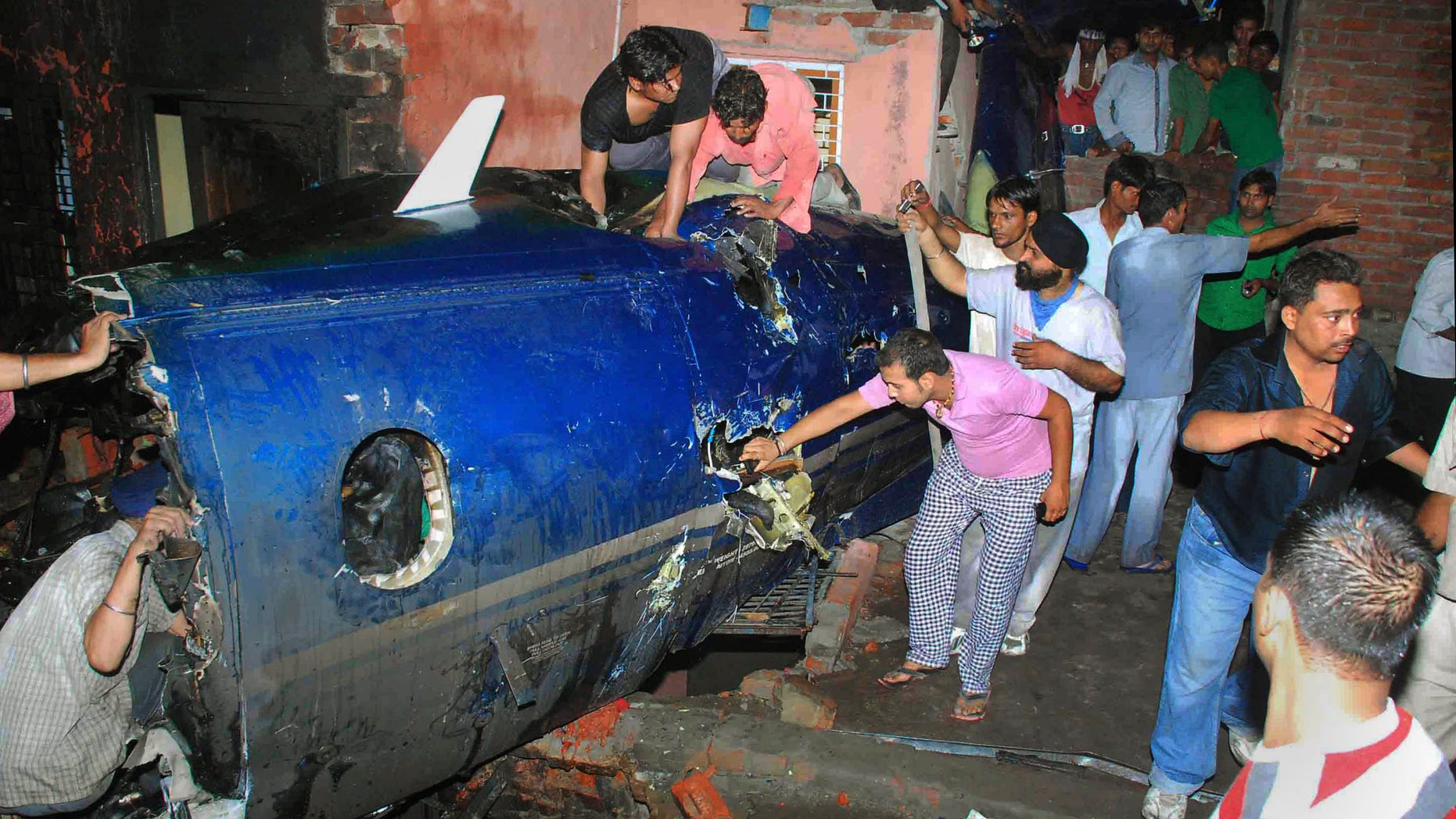 May 25: Indian residents search around the wreckage of a small plane after it crashed into a residential community in Faridabad, near New Delhi, India. A government official says the crash of a small chartered plane in a residential area on the outskirts of the Indian capital has killed at least 10 people and injured another two. (AP)