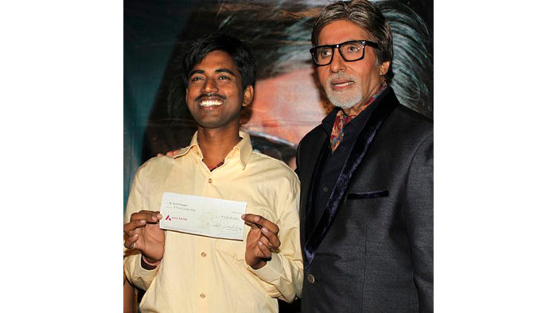 October 25: Sushil Kumar, left, with Bollywood actor Amitabh Bachchan, shows $1 million check after winning on an Indian game show, in Mumbai, India.