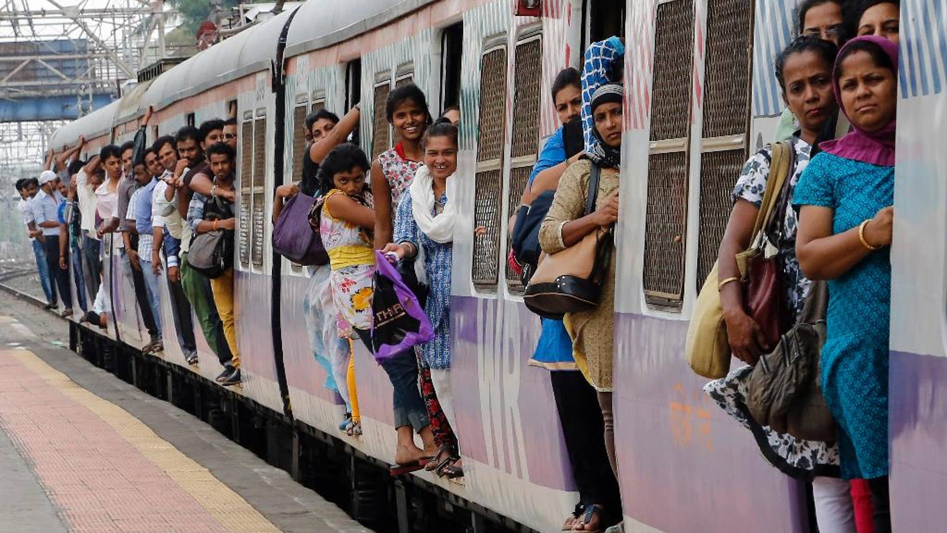 Commuters hang by doors of a crowded local train in Mumbai, India, Tuesday, July 8, 2014. India's new rail minister Sadananda Gowda on Tuesday proposed allowing foreign investment to modernize the country's cash-strapped state railways. India has one of the world's largest railways, which transports 23 million passengers a day. Indian Railways is one of the world's biggest employers with more than 1.3 million employees. The network lost 300 billion rupees ($5 billion) last year. (AP Photo/Rajanish Kakade)