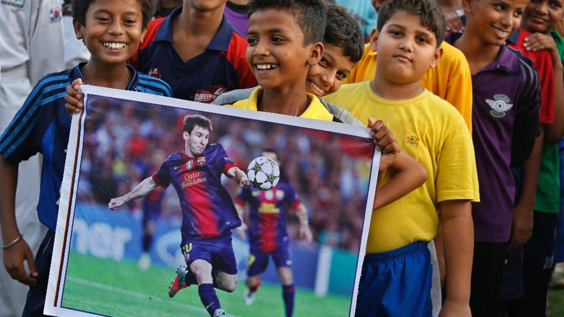 An Indian boy holds a poster of Argentina's Lionel Messi as sports enthusiasts gather at an event to celebrate the Soccer World Cup in Allahabad, India, Thursday, June 12, 2014. Nearly half the world's population, well over 3 billion spectators, is expected to watch soccer's premier event that kicks off in Brazil Thursday. (AP Photo/ Rajesh Kumar Singh)