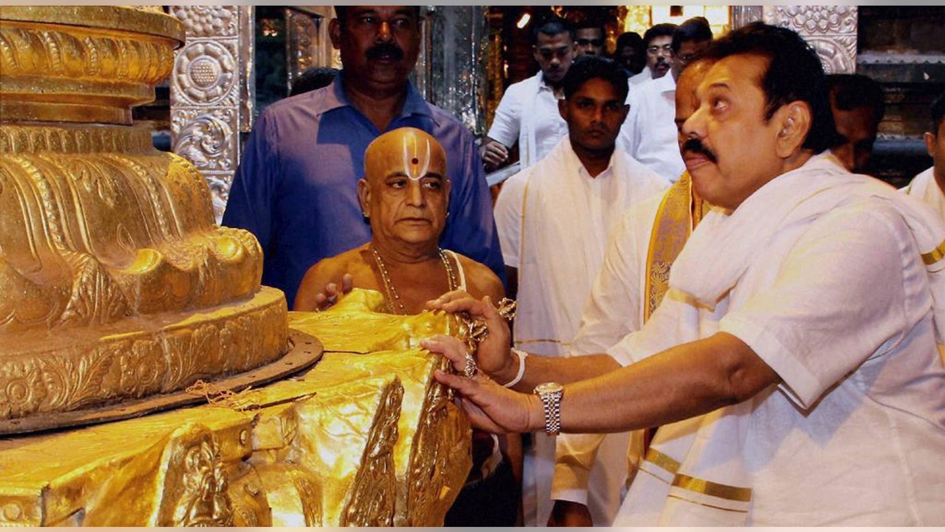 In this Wednesday, Dec.10, 2014 photo, Sri Lankan President Mahinda Rajapaksa, right, offers prayers at the Tirumala Venkateswara Hindu Temple in Tirupati, Andhra Pradesh state, India.(AP Photo/Press Trust of India) INDIA OUT