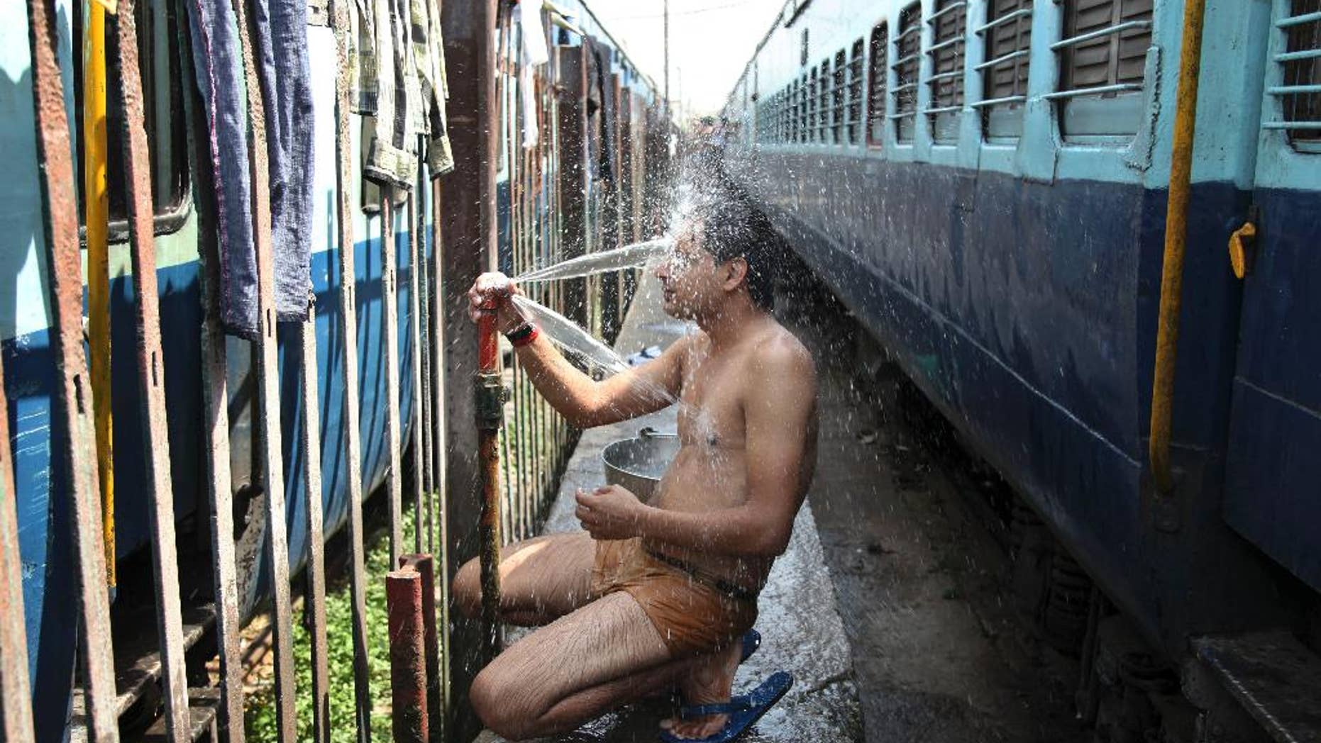 May 25, 2015: An Indian passenger takes a bath beside rail tracks on a hot summer day at a railway station in Jammu, India.