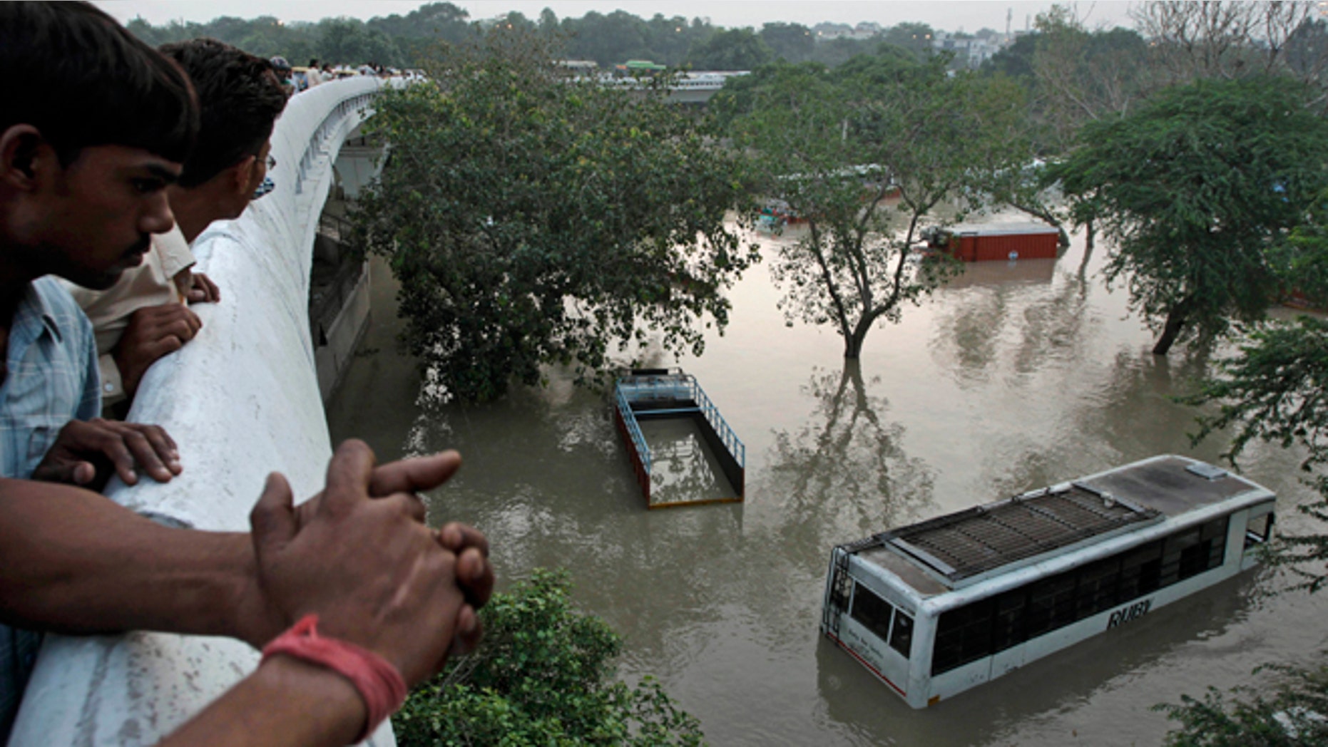 June 19, 2013: People gather to look at submerged buses and trucks in the rising Yamuna River as they stand on a flyover in New Delhi, India. Indias prime minister said Wednesday that the death toll from flooding this week in the northern state of Uttrakhand had surpassed 100 and could rise substantially.