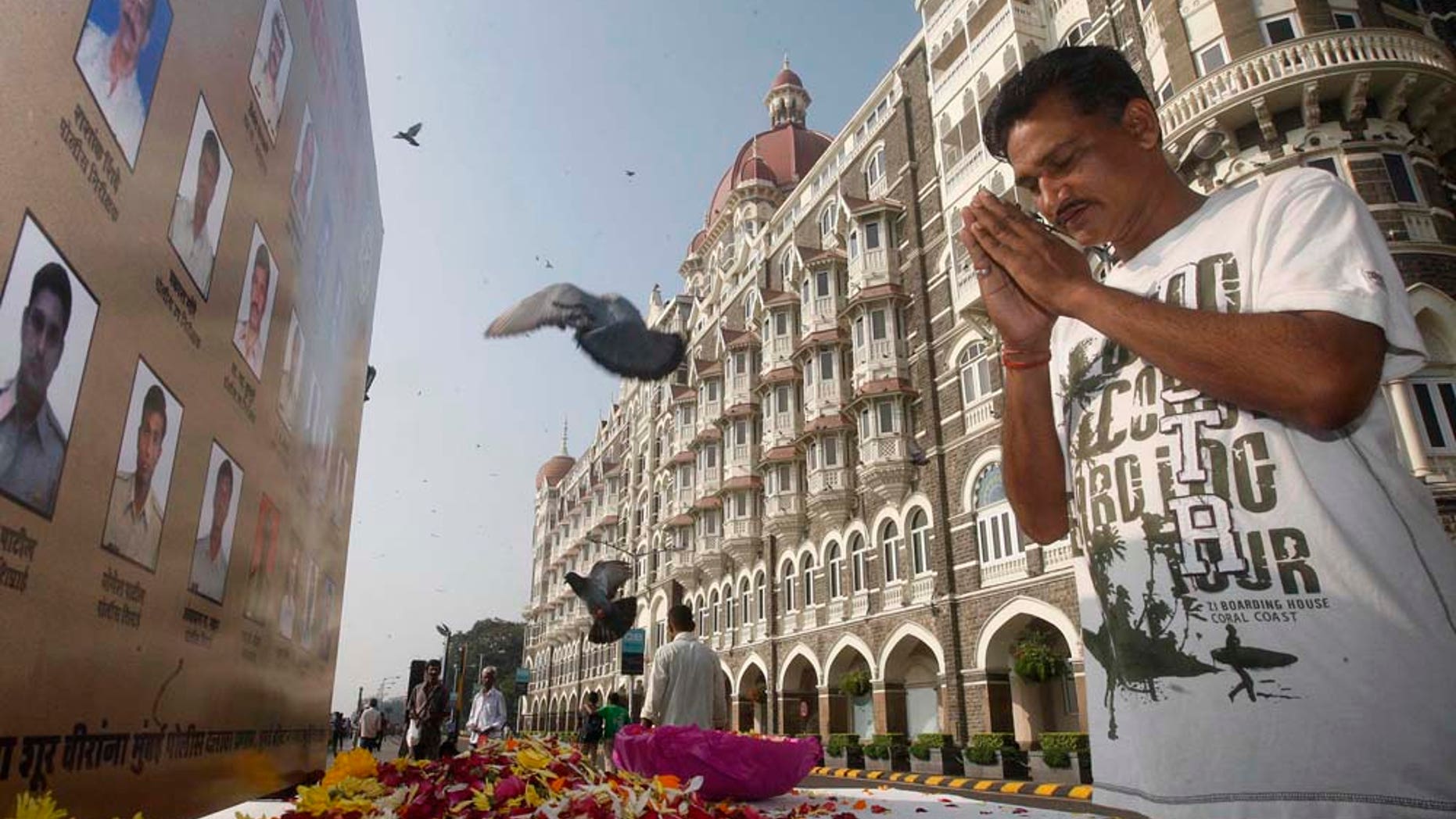 A man pays homage in front of portraits of police officers killed in the Mumbai terror attack outside the Taj Mahal Palace hotel, one of the sites of the attack, on the second anniversary of the attack in Mumbai, India, Friday, Nov. 26, 2010. India rebuked Pakistan on Thursday for not punishing the alleged masterminds of the 2008 terror attack on the Indian financial capital of Mumbai that killed 166 people. (AP Photo/Rafiq Maqbool)