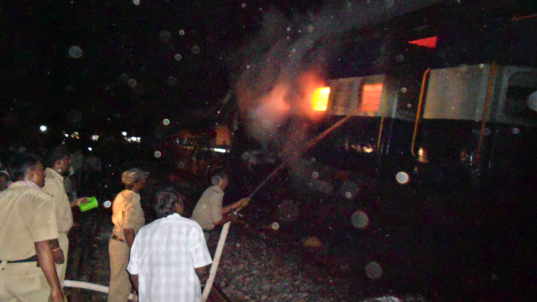 May 22, 2012: Firefighters and policemen try to douse flames on a train after an accident at a station near Penukonda.