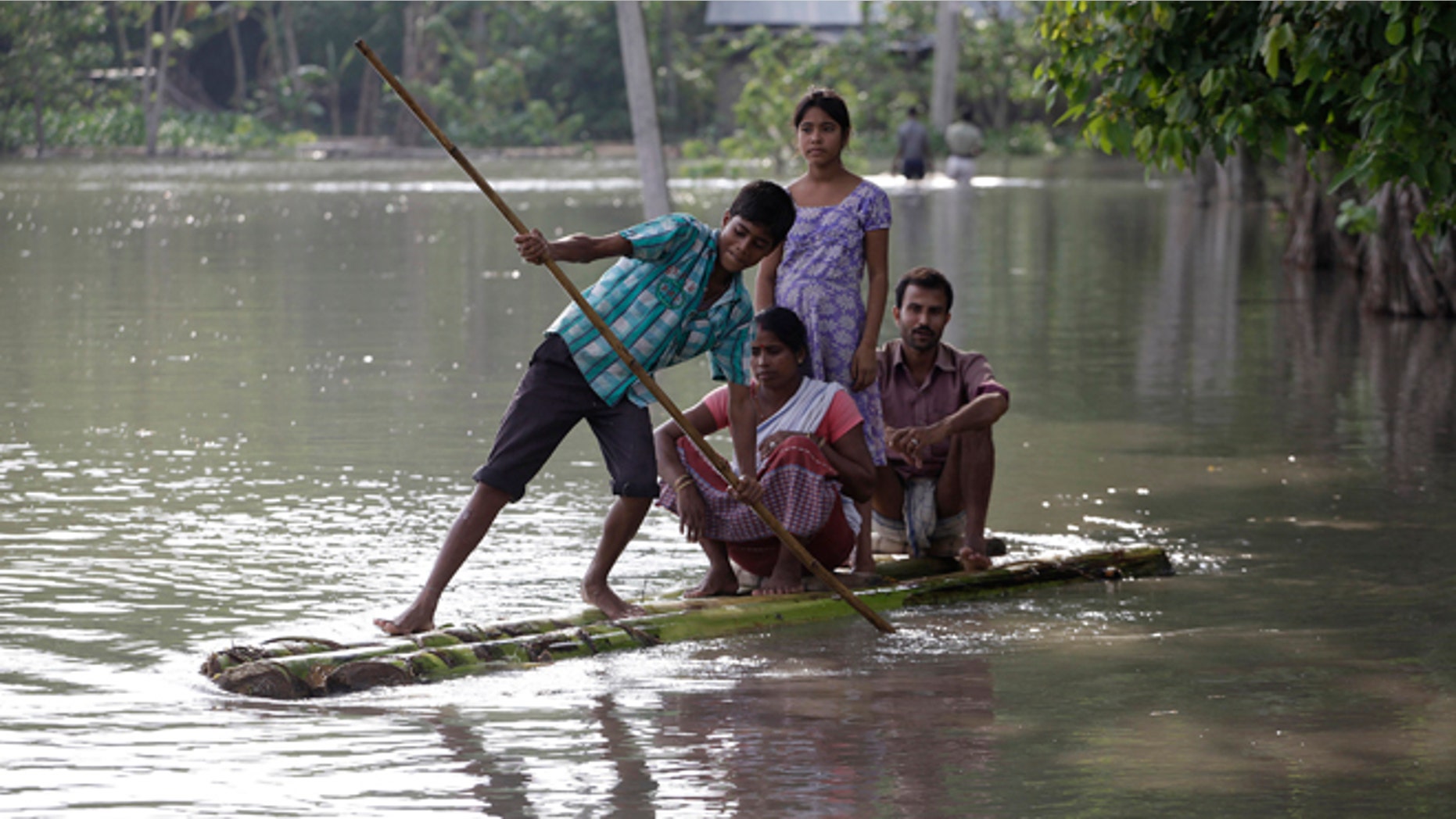 Sept. 22: A boy rows his family across floodwaters on a banana raft in Lachi Bishnupur village.