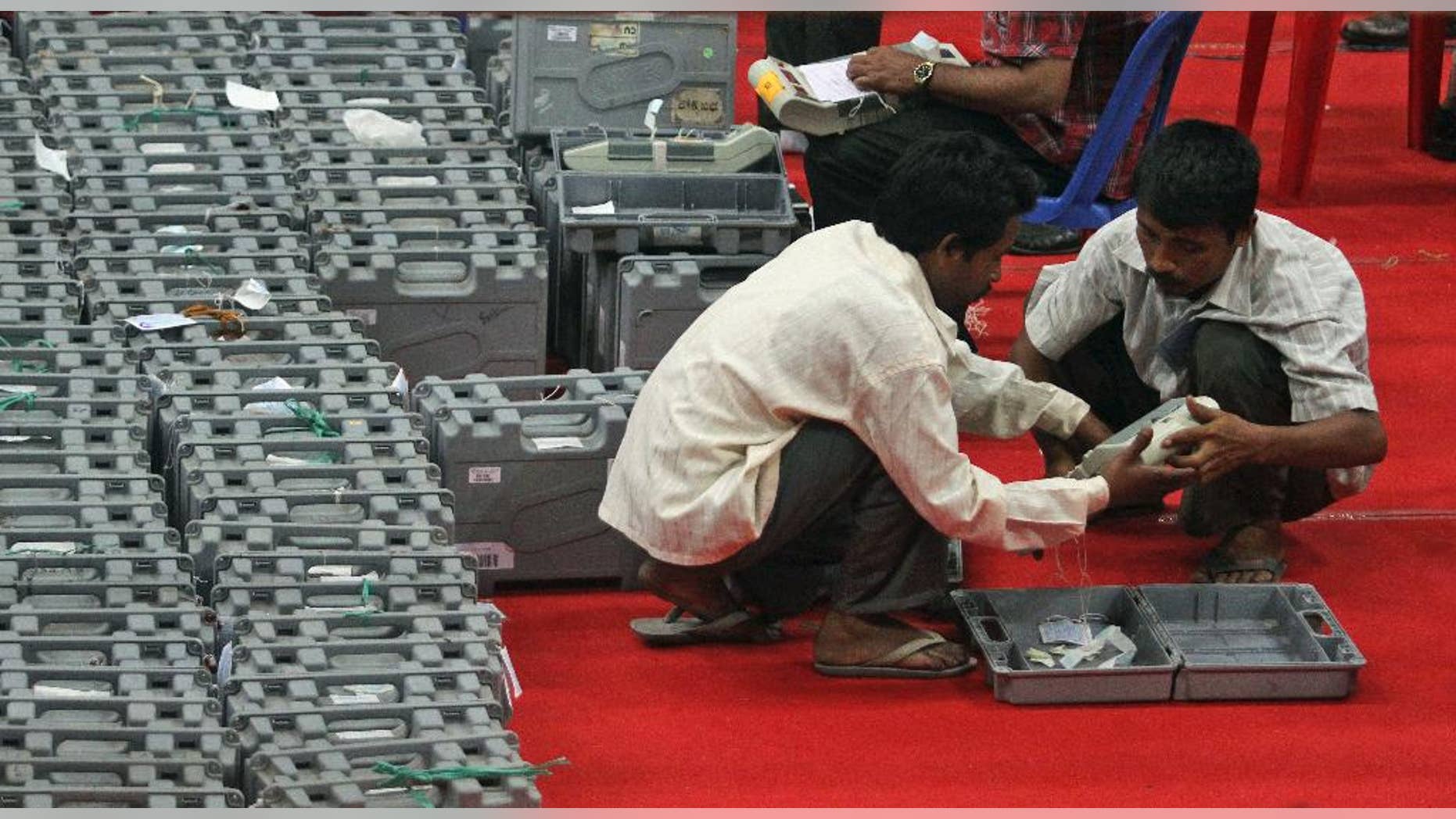 Indian workers hold an electronic voting machine during the counting of votes at a counting center in Gauhati, India, Friday, May 16, 2014. Opposition leader Narendra Modi won India's election by a landslide Friday, according to preliminary results that showed his party easily driving out the long-dominant Congress party in the most commanding election victory India has seen in more than a quarter century. The full results are expected later in the day but it's unlikely that Modi's party would see a significant reversal. (AP Photo/Anupam Nath)