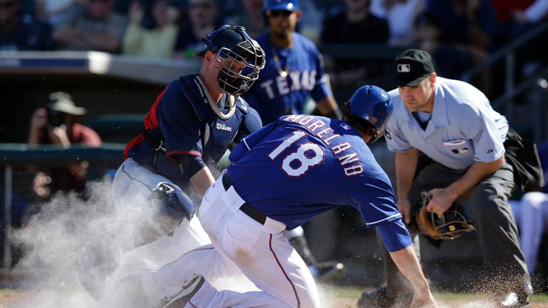 Cleveland Indians catcher Luke Carlin, tags Texas Rangers' Mitch Moreland (18) as home plate umpire David Rackley, right, watches in the fourth inning of a spring training exhibition baseball game, Monday, March 3, 2014, in Surprise , Ariz. Moreland was trying to score on a hit by J.P. Arencibia. (AP Photo/Tony Gutierrez)