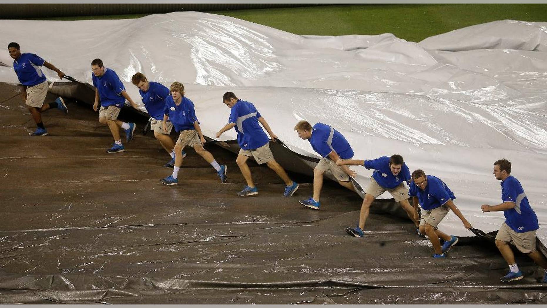 Members of the grounds crew pull the tarp on the field during a rain delay in the 10th inning of a baseball game between the Kansas City Royals and the Cleveland Indians Sunday, Aug. 31, 2014, in Kansas City, Mo. (AP Photo/Charlie Riedel)