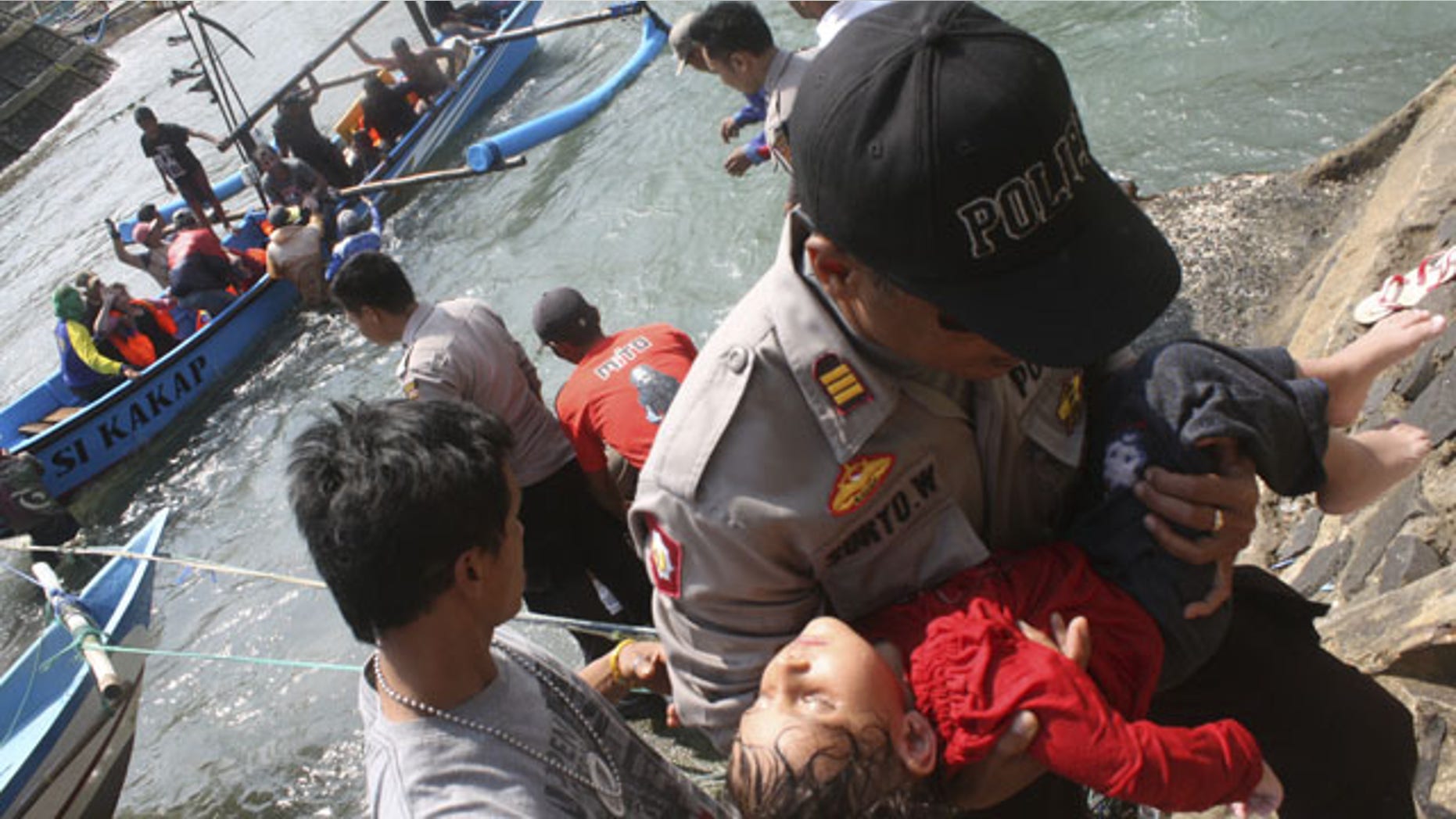 July 24, 2013: A police officer carries a child who appears to be unconscious after a boat carrying asylum seekers sank off Java island, in Cianjur, West Java, Indonesia. (AP Photo)