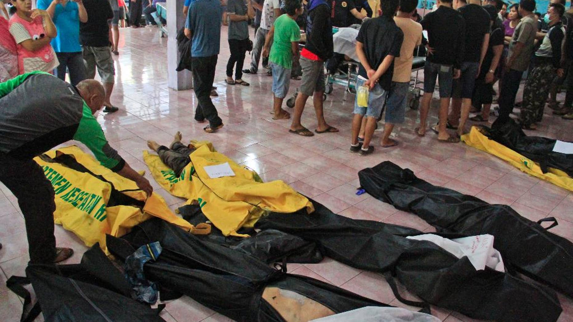 People wait to identify the bodies of their relatives among the victims of a karaoke fire, at a hospital in Manado, North Sulawesi, Indonesia, Sunday, Oct. 25, 2015. More than a dozen of people were killed in the fire that raced through a packed karaoke bar early Sunday on Indonesia's Sulawesi island, and tens others were hospitalized for smoke inhalation. (AP Photo/Ronny Adolof Buol)