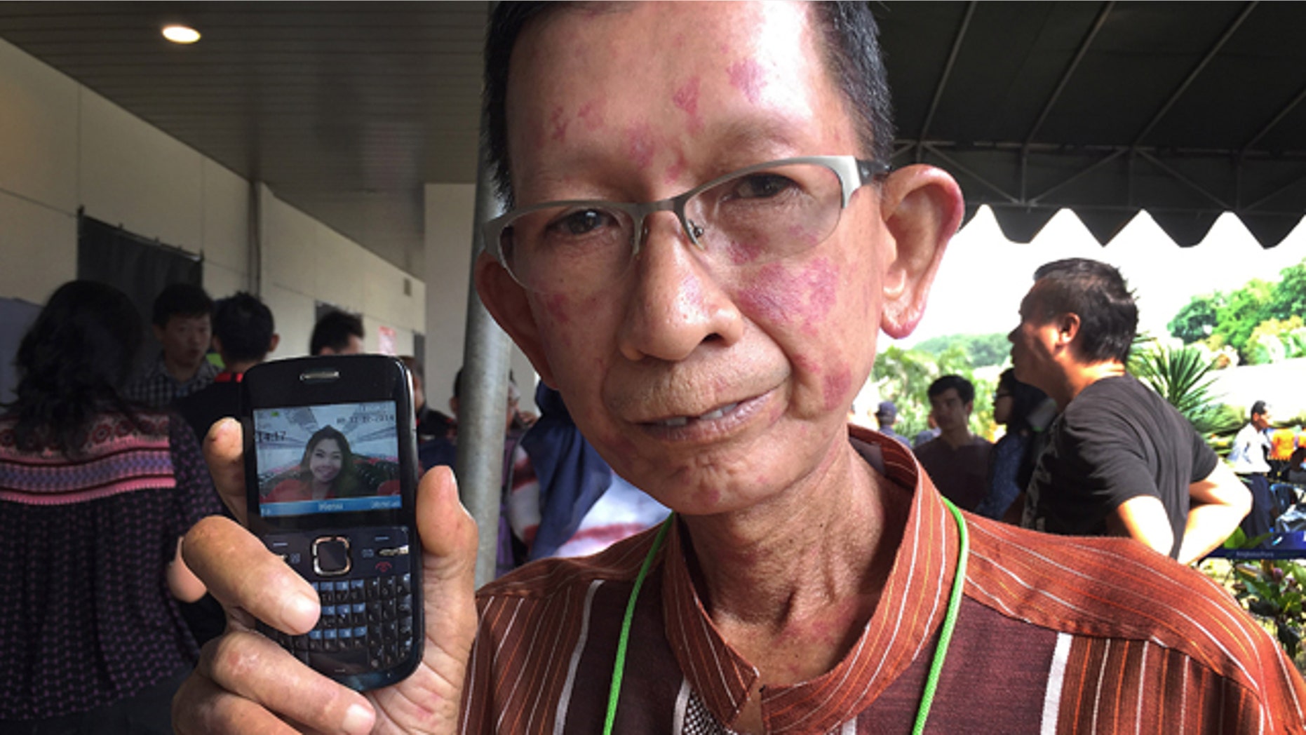 Dec. 31, 2014: Haidar Fauzie, 60, holds up a picture of his daughter Khairunnisa Haidar, 22, who was a flight attendant on AirAsia Flight 8501, at Juanda International Airport in Surabaya, Indonesia. (AP Photo/Eileen Ng)