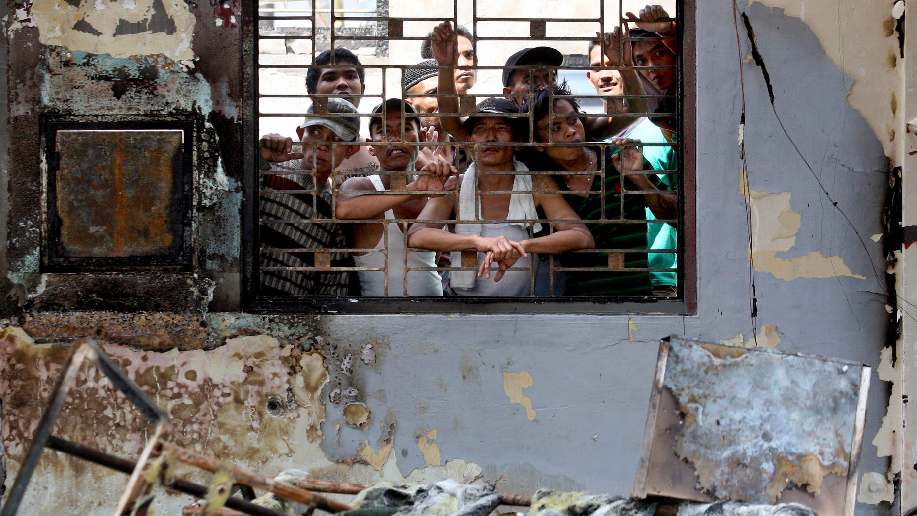 July 12, 2013 - Inmates look out from inside a burned office at Tanjung Gusta prison following a prison riot in Medan, North Sumatra, Indonesia. Security forces regained control of the crowded prison where inmates set fires and started a deadly riot that left five people dead and hundreds of prisoners, including convicted terrorists, on the loose, officials said.