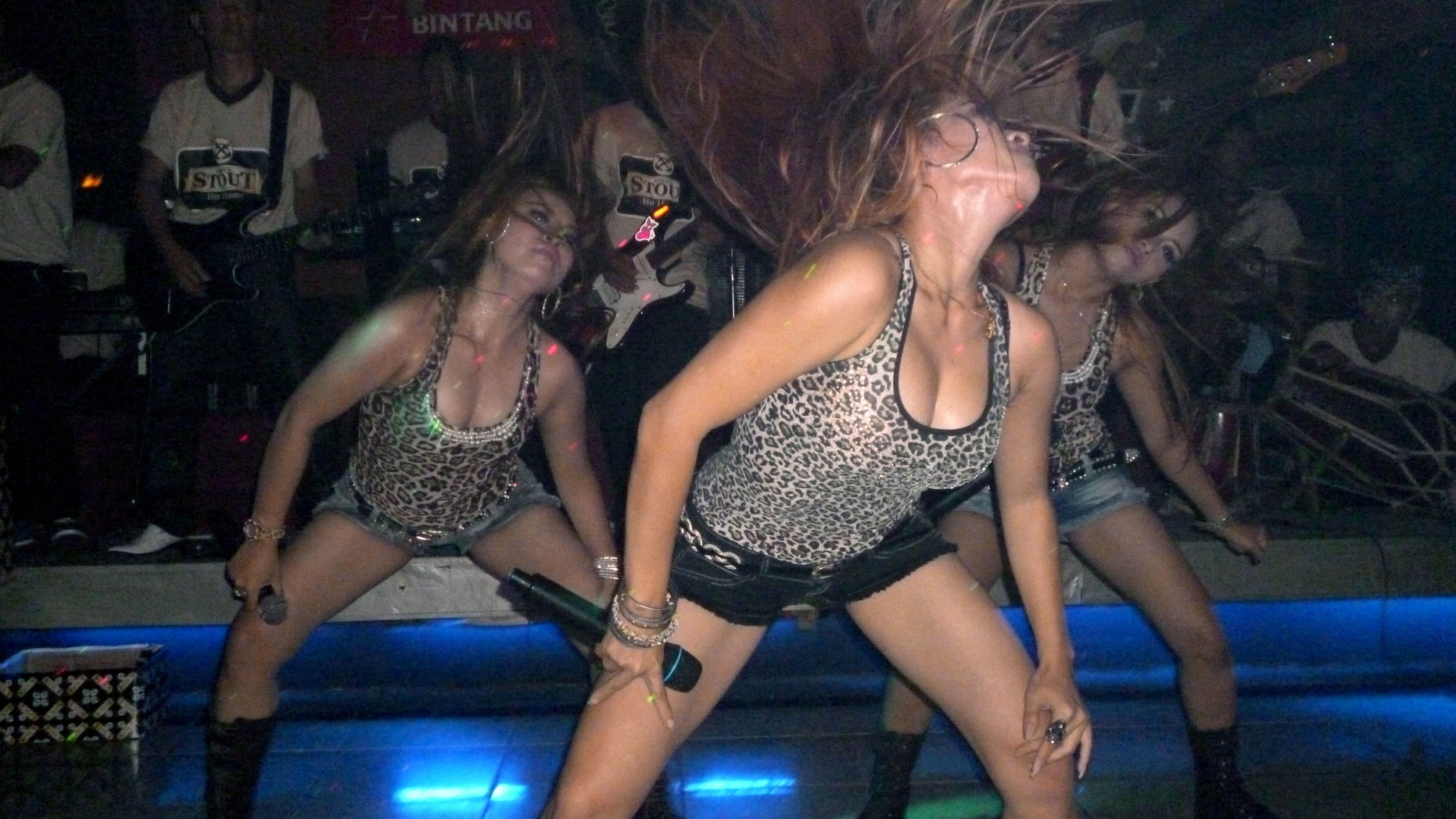 HOLD FOR STORY INDONESIA RAUNCHY SHOWS BY ROBIN MCDOWELL - In this May 25, 2012, singers perform during a dangdut show at a pub in Jakarta, Indonesia. As U.S. pop star Lady Gaga's cancelled her sold out concert in Jakarta over security concerns after Muslim hardliners threatened to use violence against her, many started to question the extremists' double standard towards the raunchy dangdut shows performed almost every night by young Indonesian women who turn up everywhere from smokey bars and ritzy nightclubs to weddings and even circumcisions. Dangdut is the most popular music among lower class people in Indonesia. (AP Photo/Robin McDowell)
