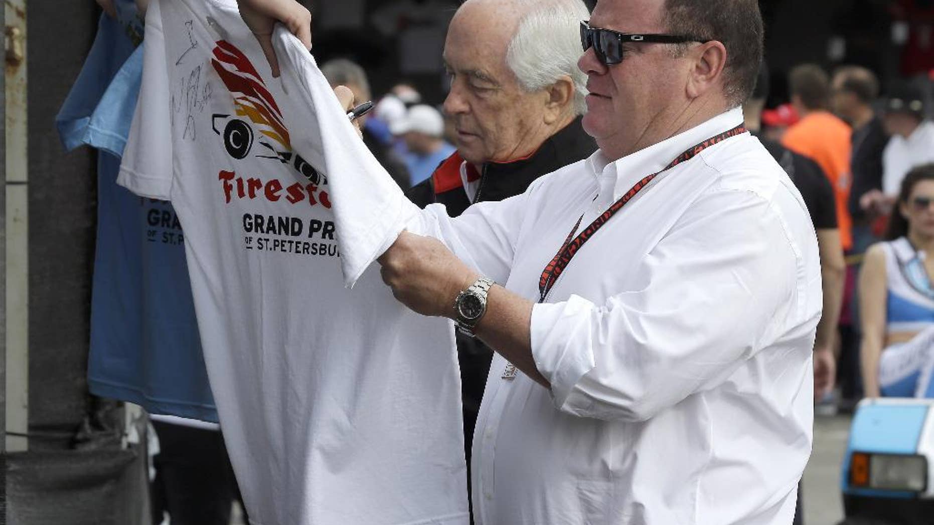 Car owners Roger Penske, left, and Chip Ganassi sign autographs for fans before practice for the IndyCar Firestone Grand Prix of St. Petersburg auto race Friday, March 28, 2014, in St. Petersburg, Fla. The race takes place on Sunday. (AP Photo/Chris O'Meara)