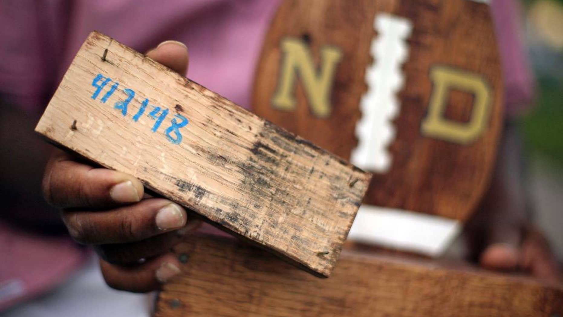 FILE - In this Aug. 14, 2015 file photo, Larry Stephney holds a piece of wood with the number 412148 written on it that is from a product made while he was an inmate at a privately run prison in Nashville, Tenn. The number refers to a section of Tennessee code that makes it illegal for jail officials to require an inmate to perform labor that results in the official’s personal gain. Stephney says inmates were required to build plaques, birdhouses, dog beds and cornhole games for officials who sold the items through an online business and at a local flea market. Two Nashville jail employees and one former employee are charged with official misconduct, accused of pocketing money from the sale of inmate-made wooden plaques and games. (AP Photo/Mark Humphrey, File)