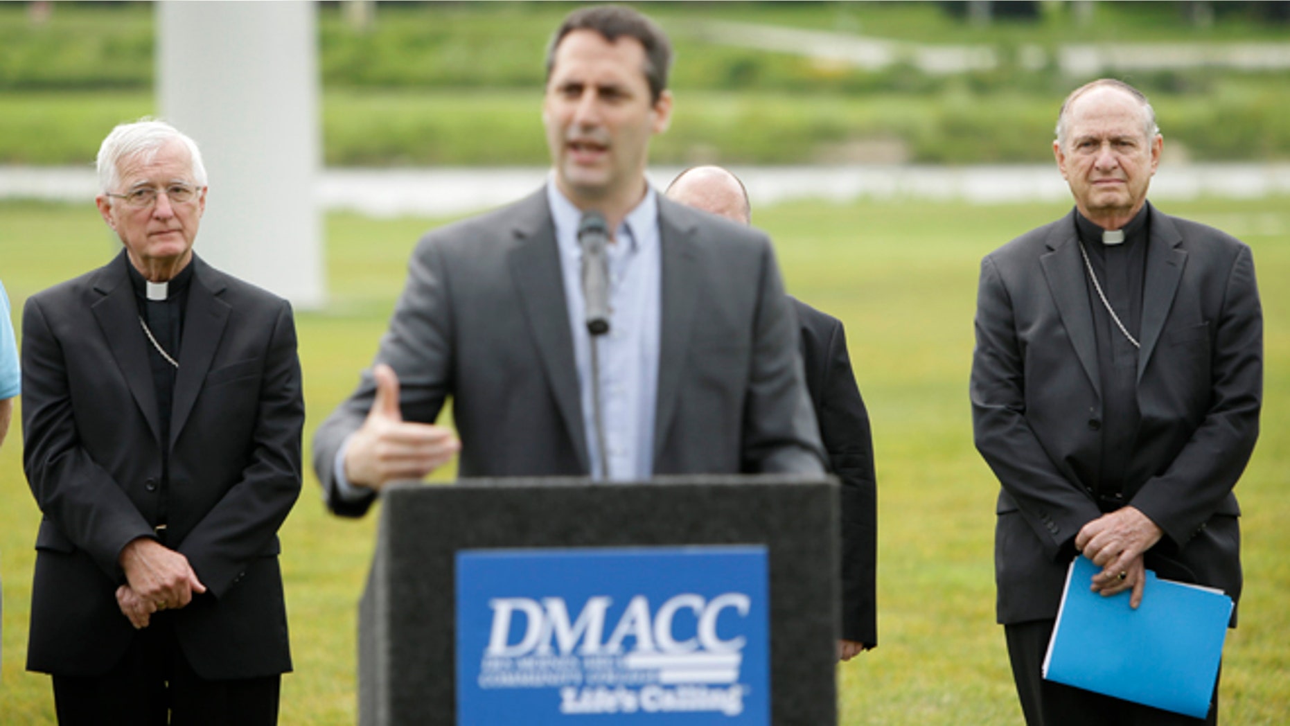 Bishop Martin Amos, of the Diocese of Davenport, left, and Bishop Richard Pates, of the Diocese of Des Moines, right, listen to Lonnie Ellis speak during a news conference, Thursday, July 2, 2015, in Ankeny, Iowa. Roman Catholic leaders in Iowa are calling for presidential candidates to focus on the environment and income inequality in 2016. (AP Photo/Charlie Neibergall)