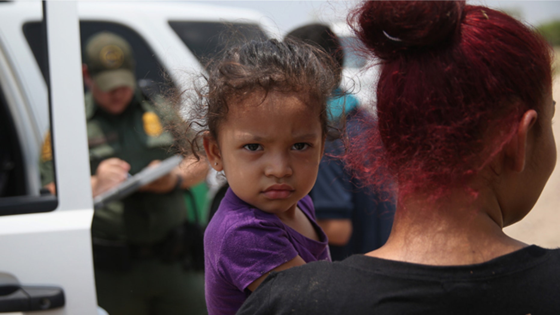 MISSION, TX - JULY 24: A mother and child, 3, from El Salvador await transport to a processing center for undocumented immigrants after they crossed the Rio Grande into the United States on July 24, 2014 in Mission, Texas. Tens of thousands of immigrant families and unaccompanied minors have crossed illegally into the United States this year and presented themselves to federal agents, causing a humanitarian crisis on the U.S.-Mexico border. (Photo by John Moore/Getty Images)