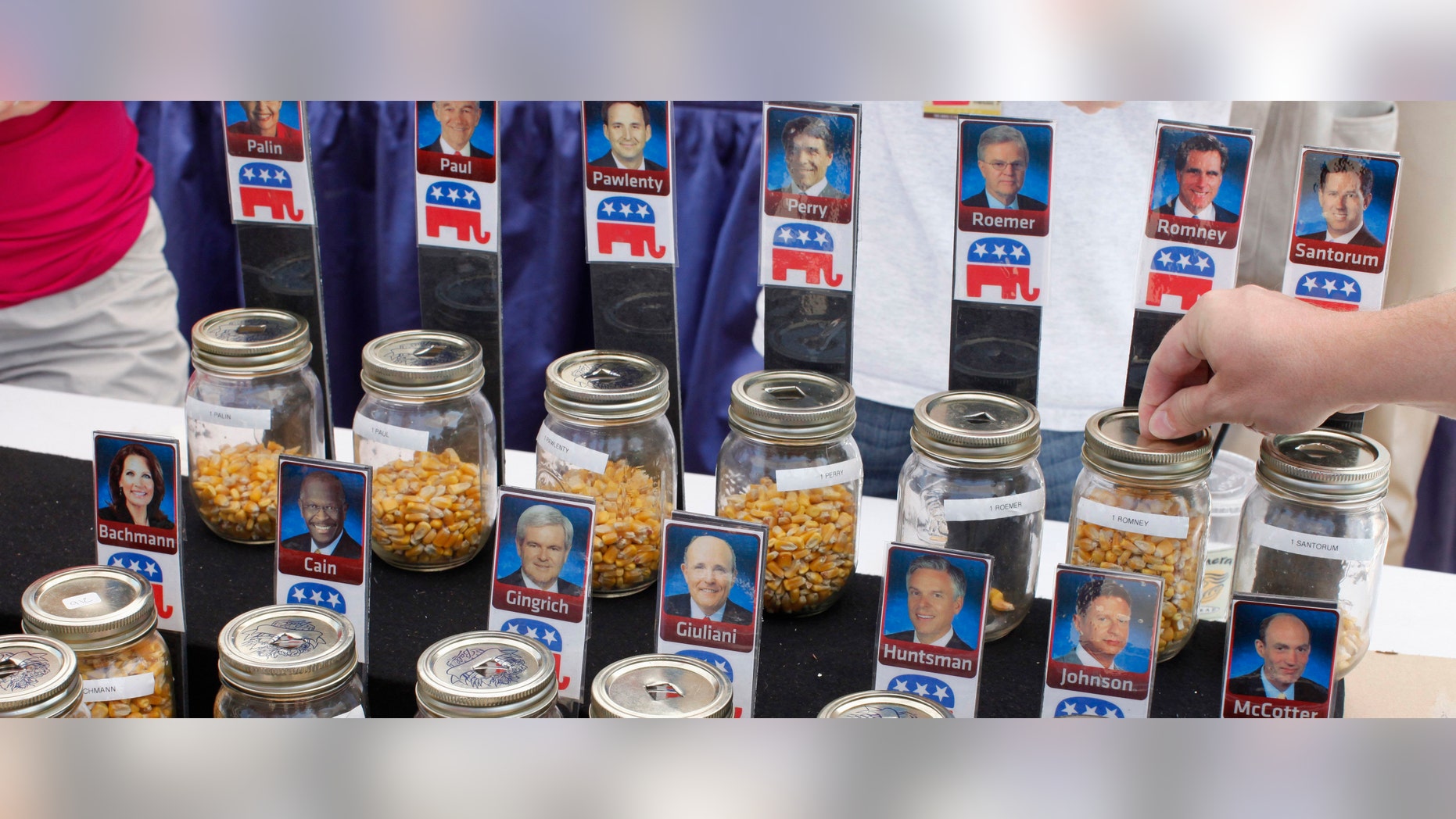 FILE - In this Aug. 12, 2011 file photo, a visitor places a kernel of corn for Republican presidential hopeful former Massachusetts Gov. Mitt Romney during an informal "corn poll" at the Iowa State Fair in Des Moines, Iowa. (AP Photo/Charles Dharapak, File)