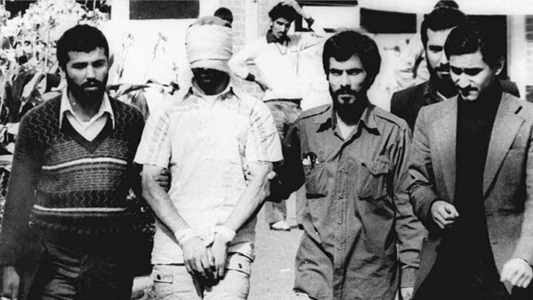 FILE - In this Nov. 9, 1979, file photo, one of the hostages being held at the U.S. Embassy in Tehran is displayed to the crowd, blindfolded and with his hands bound, outside the embassy. (AP Photo)
