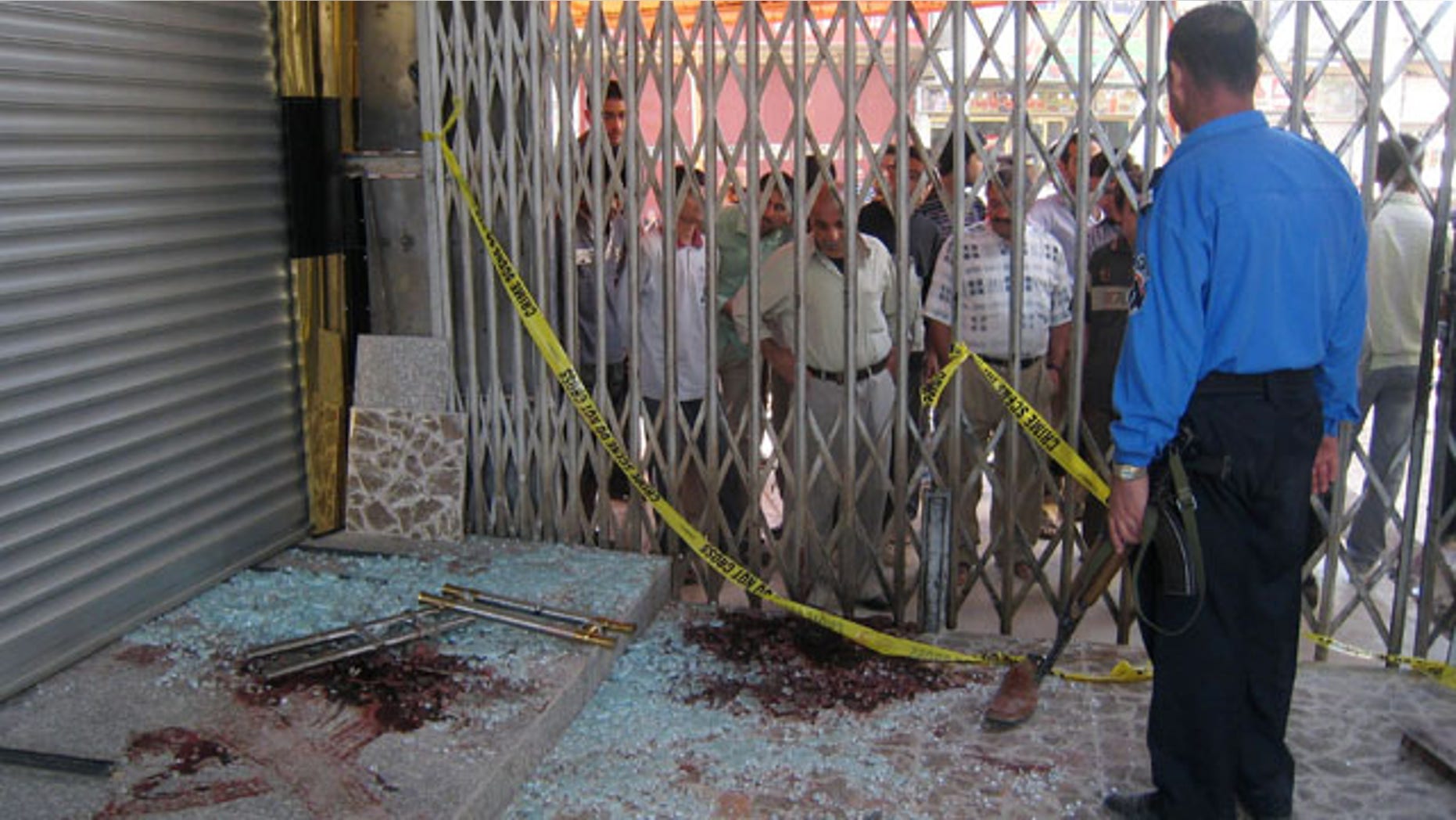 Oct. 27: An Iraqi policeman stands guard and people take in the scene the morning after gunmen stormed a jewelry store in Kirkuk, 180 miles north of Baghdad, Iraq.