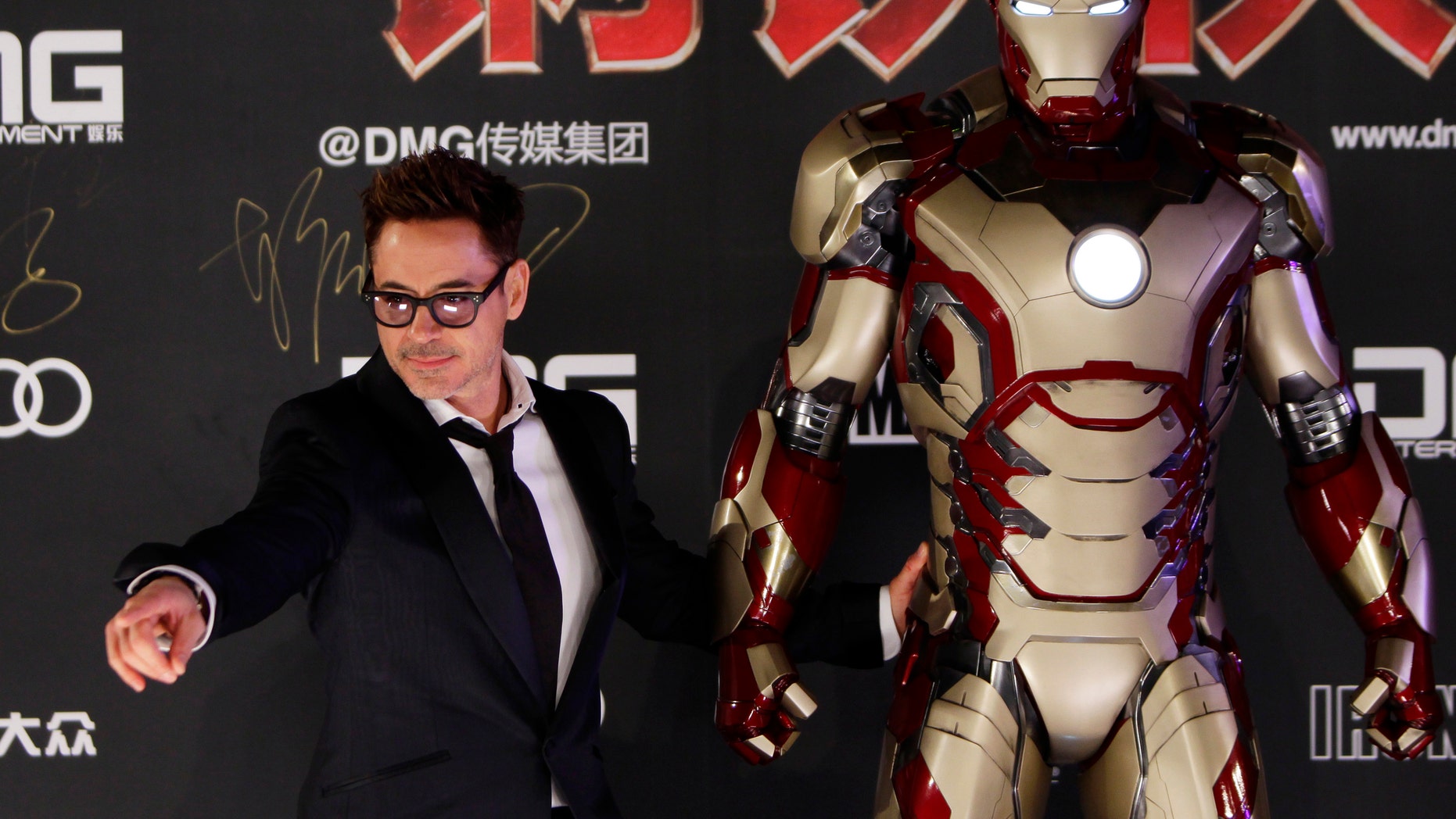 Cast member Robert Downey Jr. poses for a photo with an Iron Man figure during a promotional event of the movie "Iron Man" April 6, 2013.