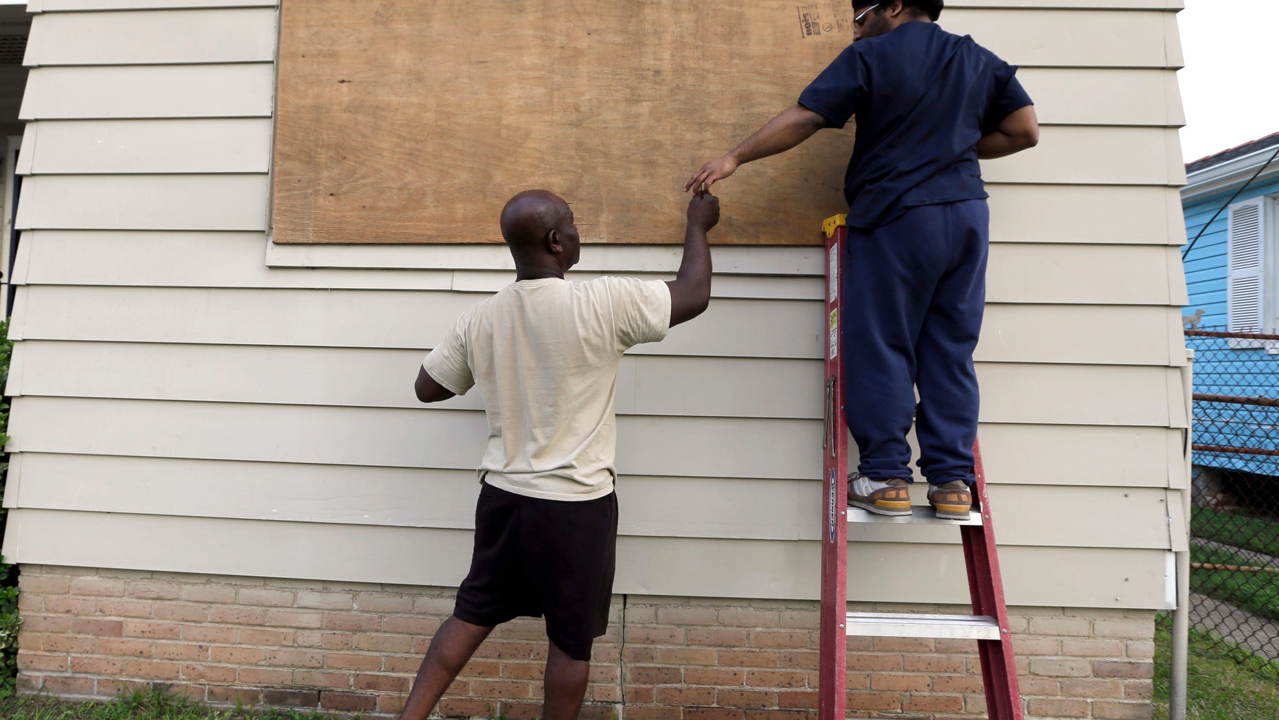 Aug. 28, 2012: Stacey Davis, left, hands a screw to his son as they board up windows on their home before Hurricane Isaac hits in New Orleans.