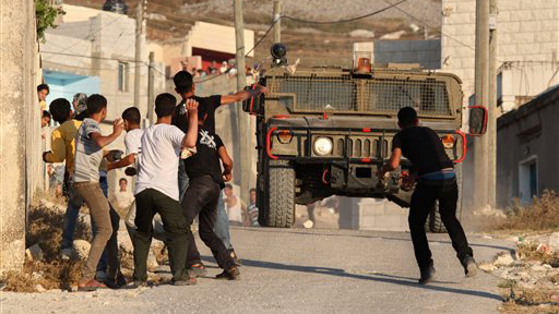 July 3, 2011: Palestinian youths hurl stones at Israeli troops during clashes over farming land between the Jewish settlement of Yitzhar and the nearby West Bank village of Asira, near Nablus.
