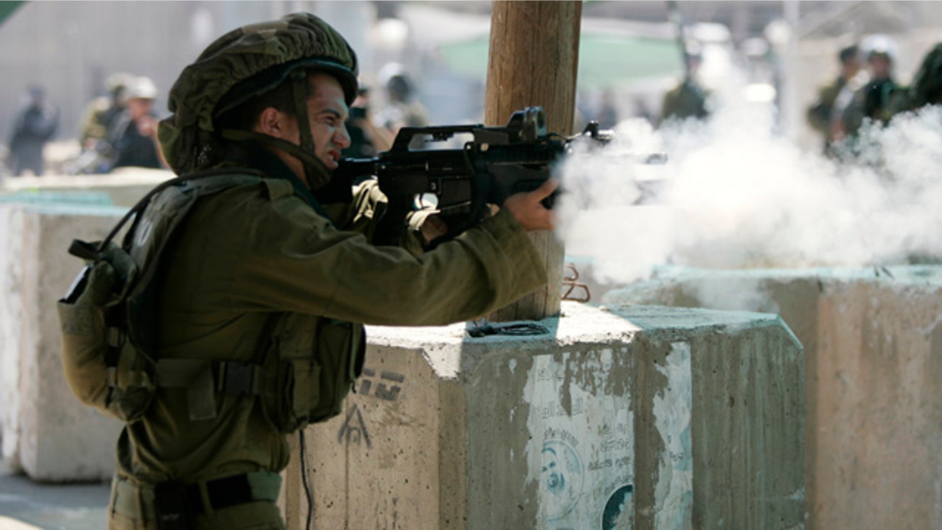 Aug. 26, 2011: An Israeli soldier fires tear gas canisters at Palestinian protesters during a protest march at the Qalandia checkpoint between the West Bank city of Ramallah and Jerusalem.