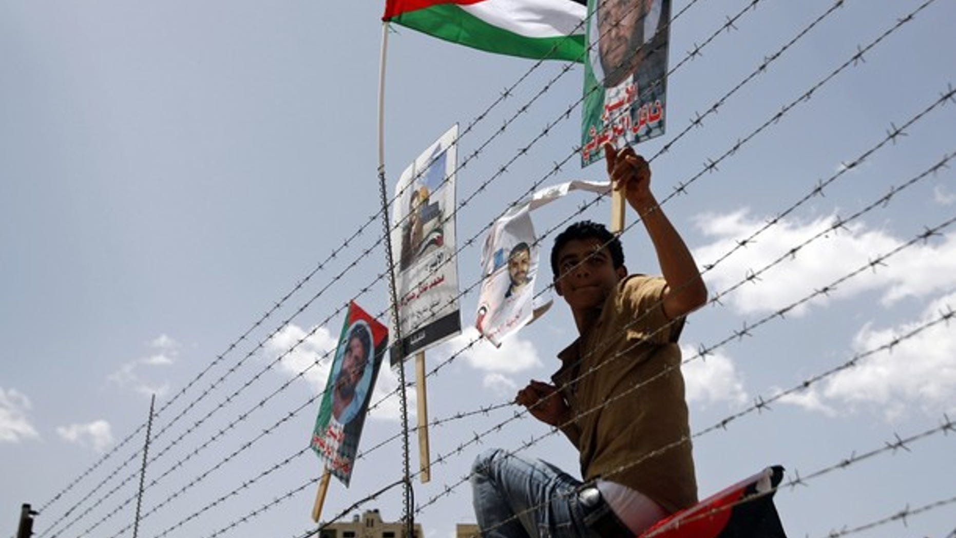A demonstrator places a poster depicting a Palestinian prisoner, on a fence during a protest outside Ofer prison, near the West Bank city of Ramallah, April 17, 2011, calling for the release of Palestinian prisoners from Israeli jails.