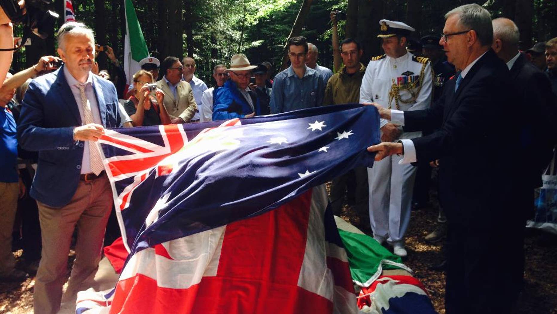 Australian ambassador to Italy, Mike Rann, right, lays the Australian flag on the occasion of the unveiling of a memorial dedicated to the Australian aviator Bert Hinkler in Castel San Niccolò near Arezzo, Tuscany, central Italy, Sunday, Aug. 2, 2015. The pilot died in an accident 1933 and for decades it has been unclear where he exactly fell, but thanks to discovery of new photos and the effort of local researchers it was possible to find the crash point on the Pratomagno mountain, in Arezzo province. (AP Photo/Paolo Santalucia)