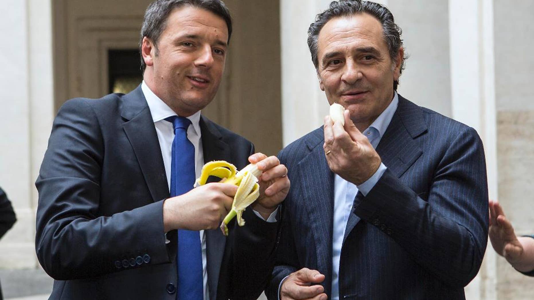 Italian premier Matteo Renzi, left, and Italian national soccer team coach Cesare Prandelli share a banana in solidarity to Barcelona Brazilian player Dani Alves, during a ceremony in Rome, Monday, April 28, 2014. Alves, who is black, was about to take a corner in Sunday's 3-2 win at Villarreal's El Madrigal Stadium when a banana landed on the pitch in front of him. The Brazil international picked it up, peeled it and ate some of it before throwing the rest aside. After the match, Alves said humor was the best way to combat racism in sport. That sentiment has led fellow football players, officials and even political figures from around the globe to respond with solidarity by picturing themselves eating a banana. (AP Photo/Roberto Monaldo, Lapresse) ITALY OUT