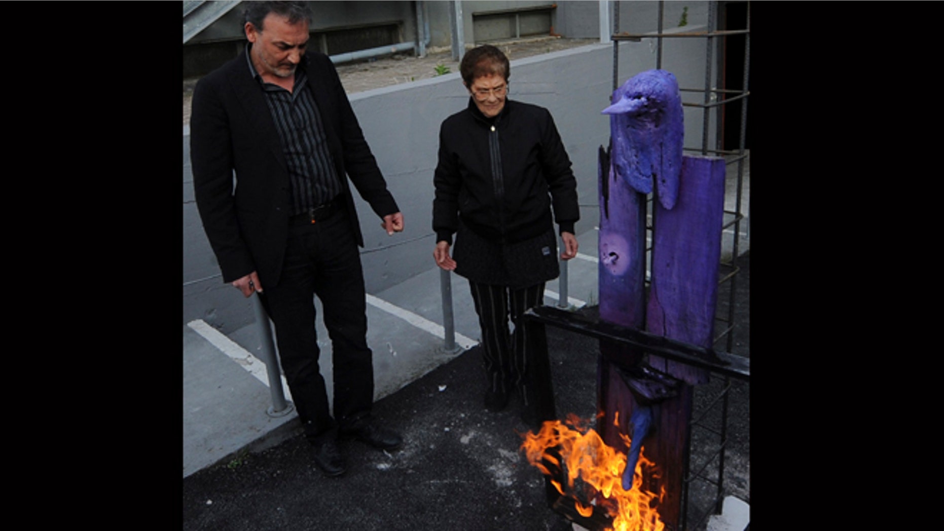 April 18, 2012: Antonio Manfredi, left, director of the Casoria Contemporary Art Museum, and Italian artist Rosaria Matarese burn one of Matarese's creations in front of the museum, near Naples.