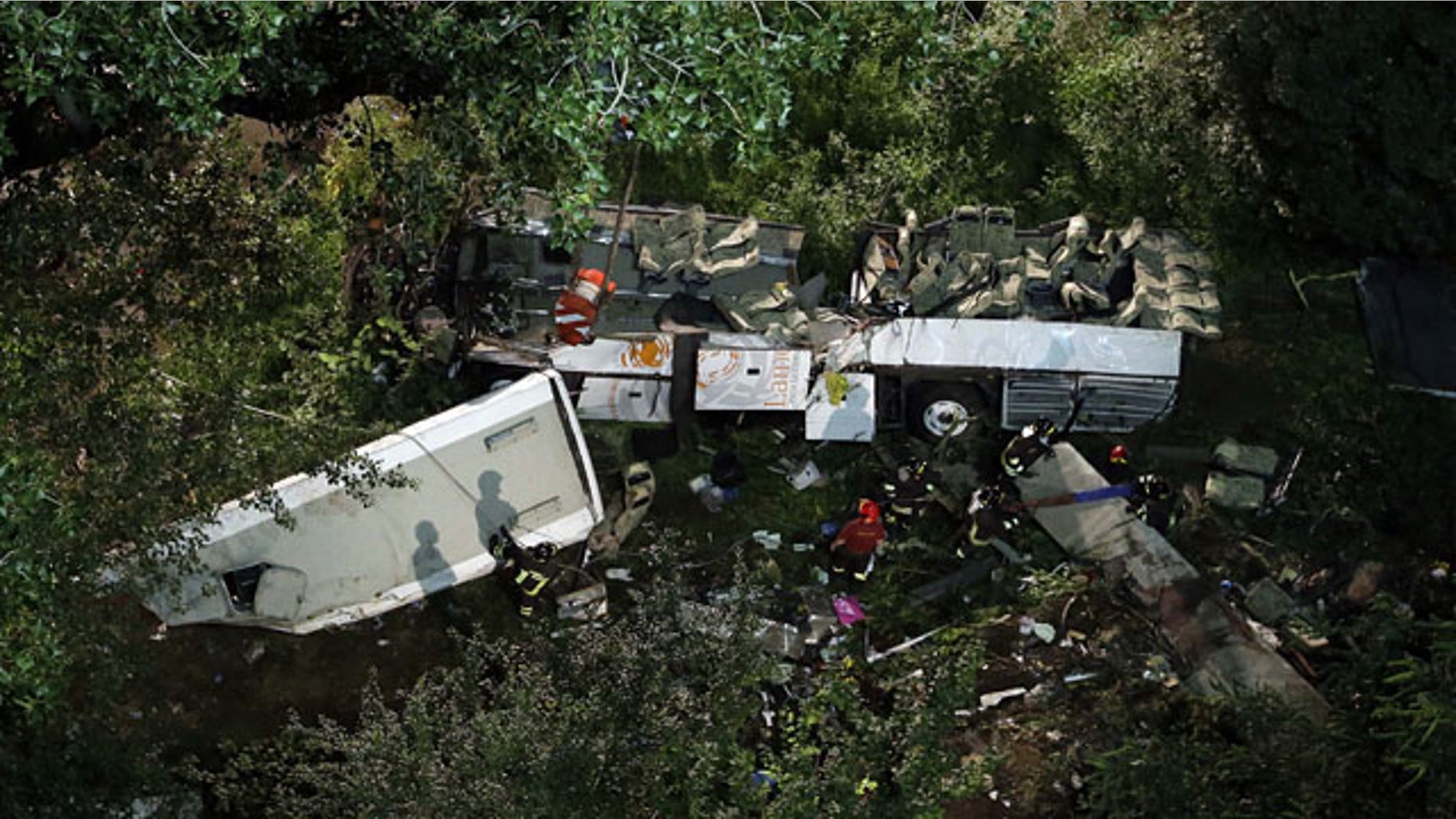 July 29, 2013: Firefighters work on the wreckage of a bus that plunged off the A16 highway near Avellino in southern Italy. (AP Photo)