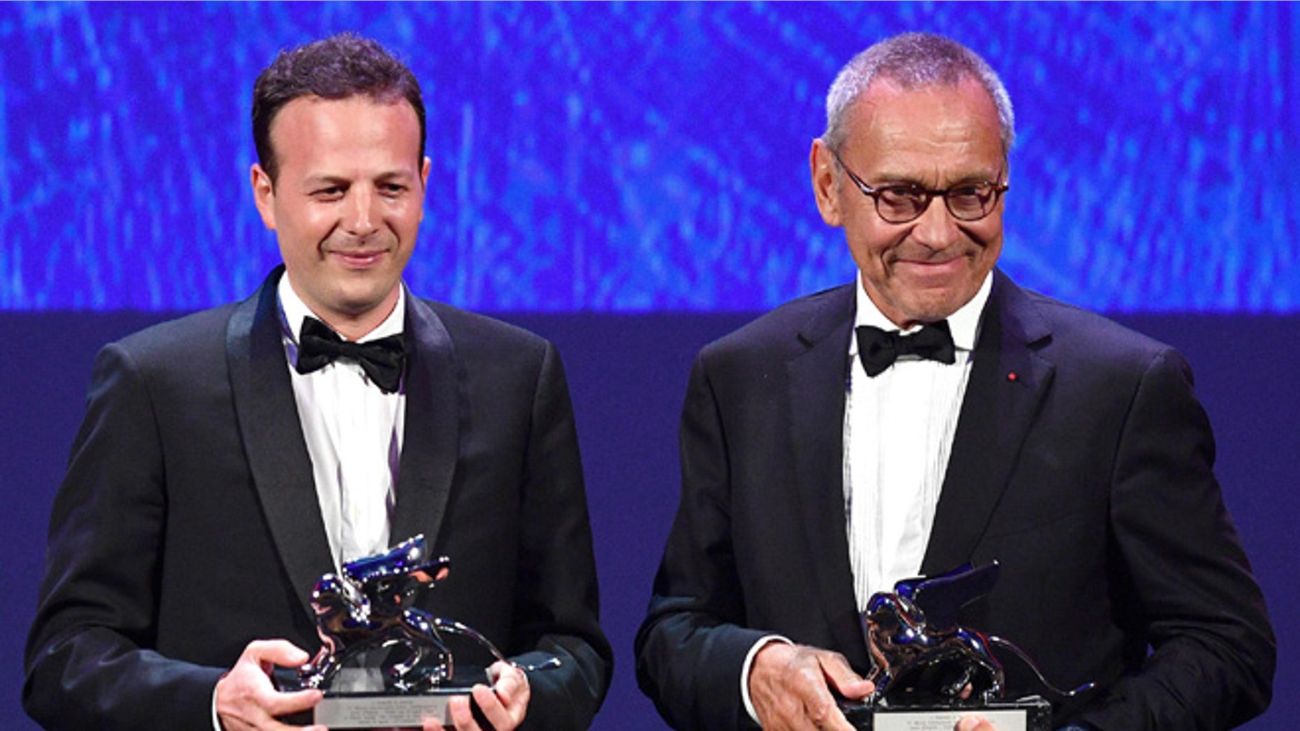 Mexican film director, producer and screenwrite Amat Escalante, left, holds the Silver Lion award for his movie "La Region Salvaje" (The Untamed) flanked by Russian director Andrei Konchalovsky, holding the Silver Lion award for his movie "Paradise" during the awards ceremony of the 73rd Venice International Film Festival, in Venice, Italy, Saturday, Sept. 10, 2016. (Ettore Ferrari/ANSA via AP)