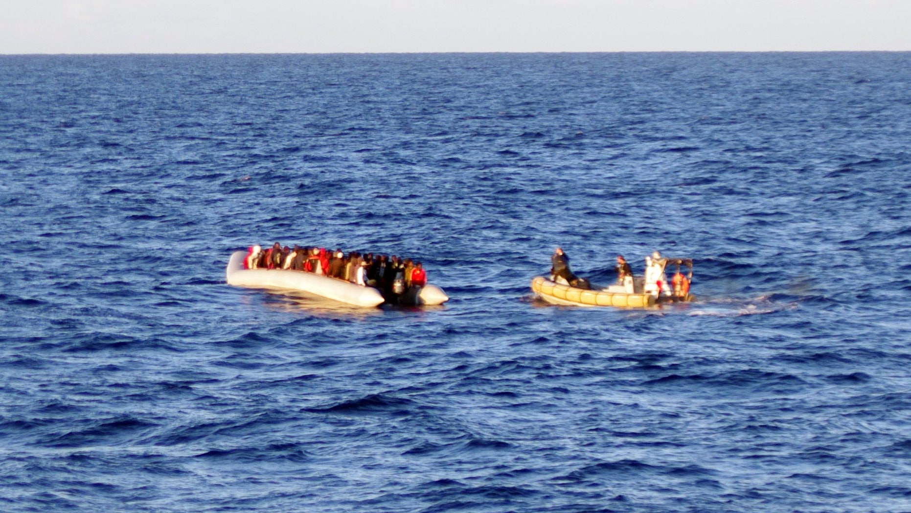 Dec. 4, 2014 - Rescue crew on a dinghy, right, approaches migrants on a boat some 40 miles from the Libyan capital, Tripoli. Rescue crews discovered 17 bodies in a migrant boat off Libya, the first reported deaths since the European Union took over Mediterranean rescue operations, the Italian navy said Friday.