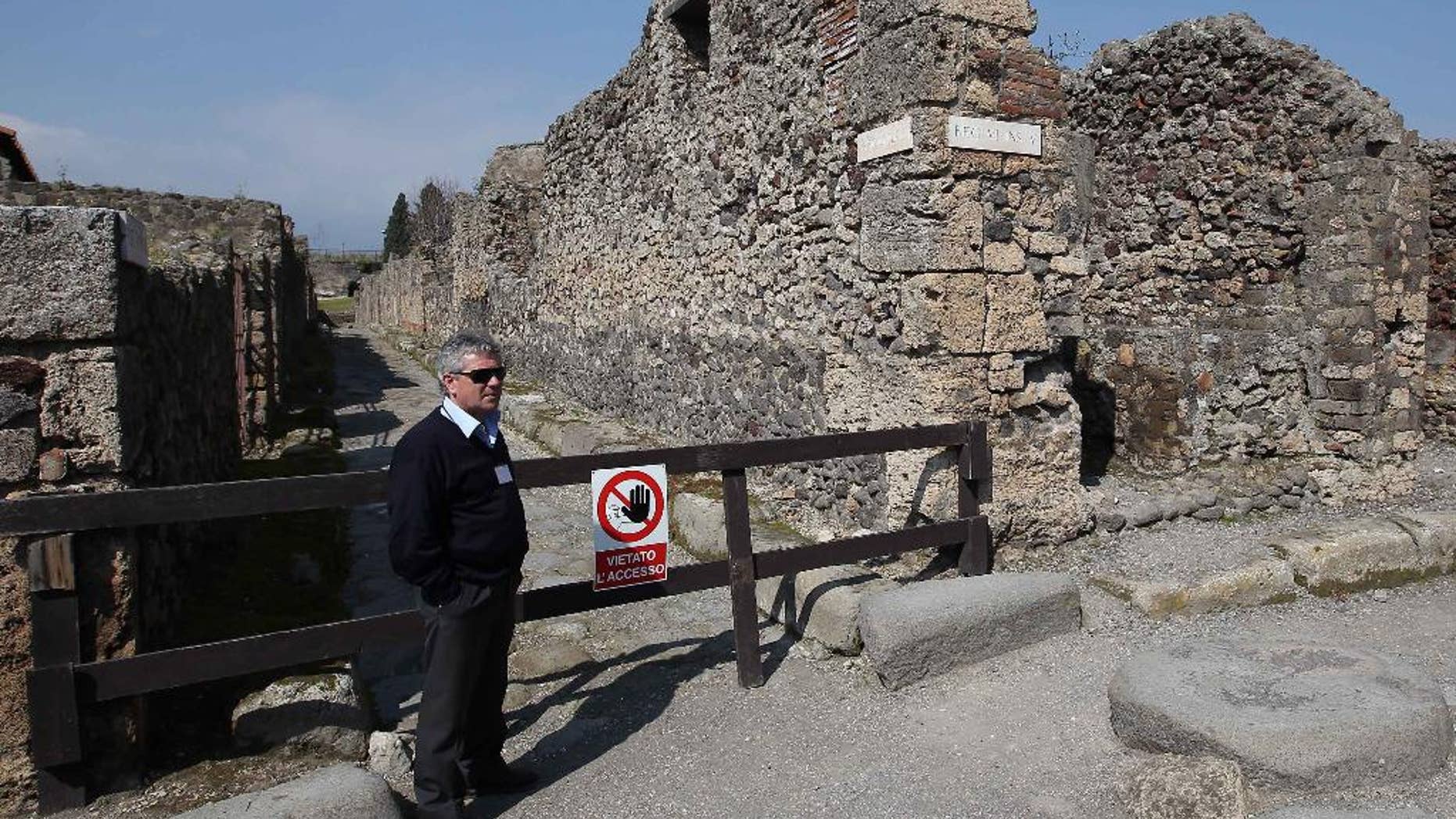 A man stands by the area where thieves pried off a chunk of an ancient fresco of the Greek goddess Artemis from the walls of Pompeii, Italy, Tuesday, March 18, 2014. Pompeii's archaeological authorities said Tuesday the theft occurred on March 12 in the "Home of Neptune," in an area of Pompeii's sprawling excavation site not currently open to the public. The thieves used a metal object to scrape off the upper corner of the fresco, making off with a faded, 20-centimeter image of Artemis, the Pompeii authorities said in a statement. It's the latest setback for the popular tourist site, which has seen several walls collapse in recent months due to heavy rains. Similar collapses in recent years have prompted an infusion of EU funds. (AP Photo/Marco Cantile, Lapresse)