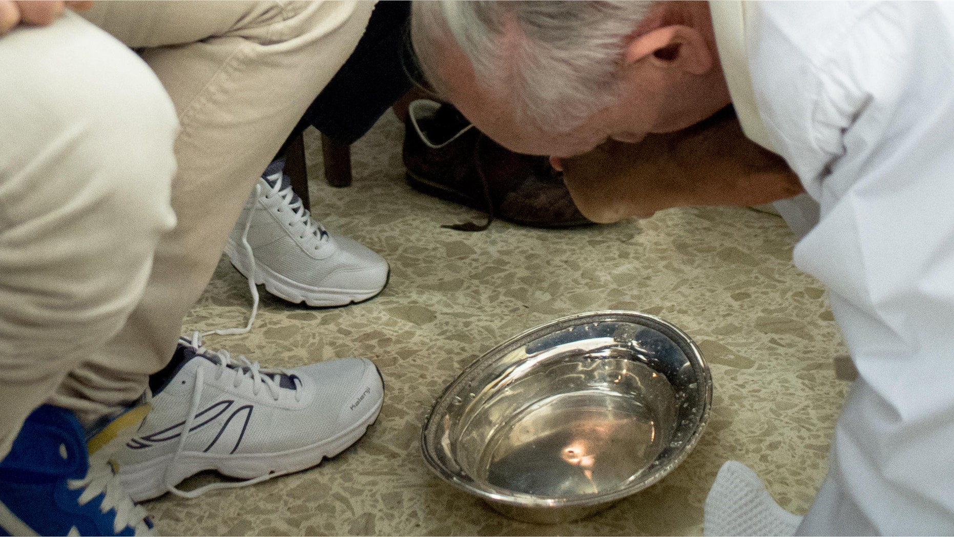 In this photo provided by the Vatican newspaper L'Osservatore Romano, Pope Francis, right, kisses the foot of an inmate at the juvenile detention center of Casal del Marmo, Rome, Thursday, March 28, 2013.