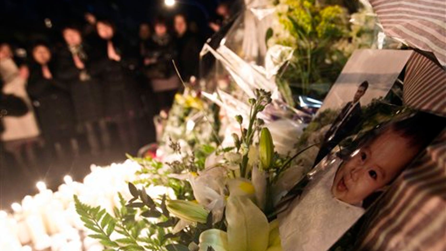 Jan. 5: Chinese immigrants pray after placing candles and flowers where the night before a Chinese immigrant and his baby, shown in the pictures at right, were killed as he tried to resist during a robbery, in Rome.