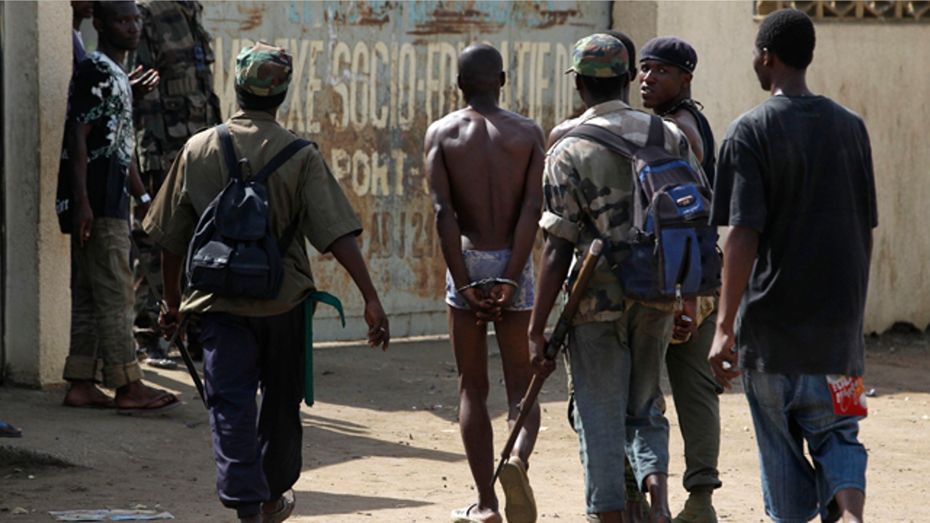April 19: Republican forces soldiers lead a handcuffed alleged militiaman loyal to Laurent Gbagbo into a social center where thousands have sought refuge from fighting in the Youpougon neighborhood, in Abidjan, Ivory Coast.