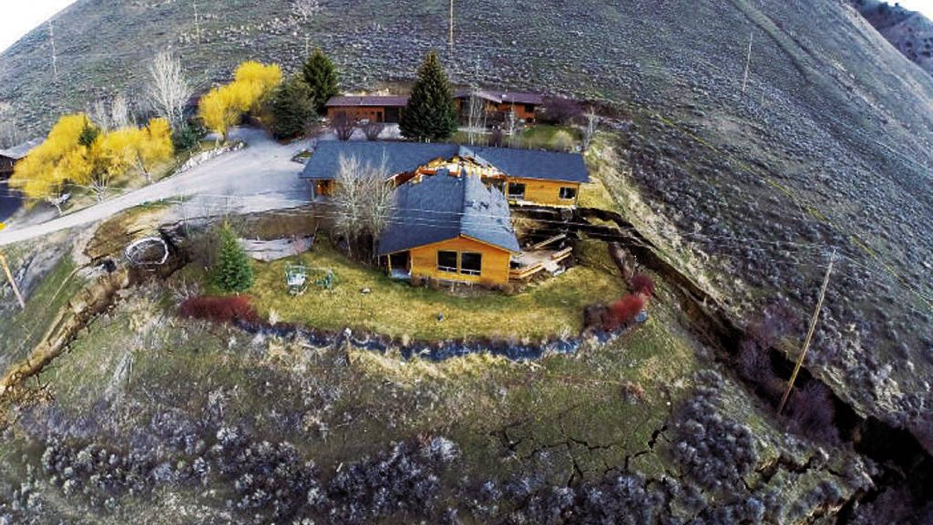 FILE - This April 18, 2014 aerial image provided by Tributary Environmental shows a home damaged by a landslide in Jackson, Wyo. Town officials say they don’t have enough time left before cold weather arrives to get going on a project to permanently stabilize a slow-moving landslide that tore one house in two and cut off access to dozens of other homes last spring. The work will begin next year. Meanwhile, next year’s spring thaw presents a concern but for now the slide only is moving at about an inch or two per month, according to George Machan, the chief engineer consulting with town officials on the situation said Tuesday, Sept. 30, 2014. (AP Photo/Tributary Environmental) NO SALES